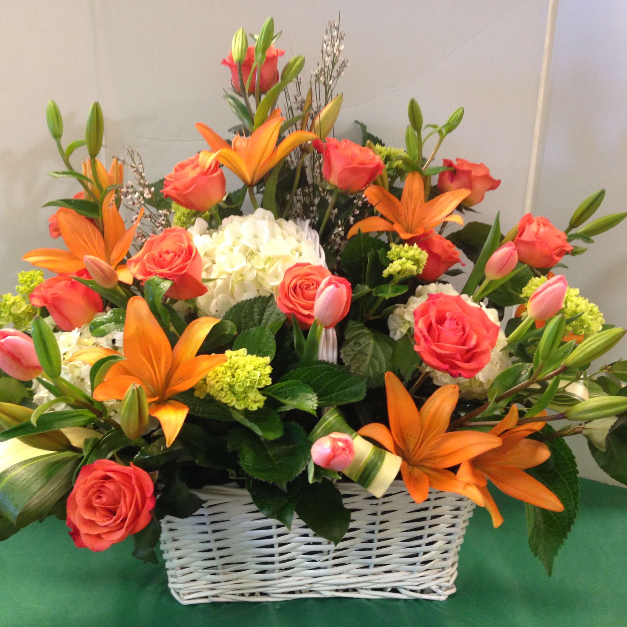 Orange lilies and coral roses in a white basket