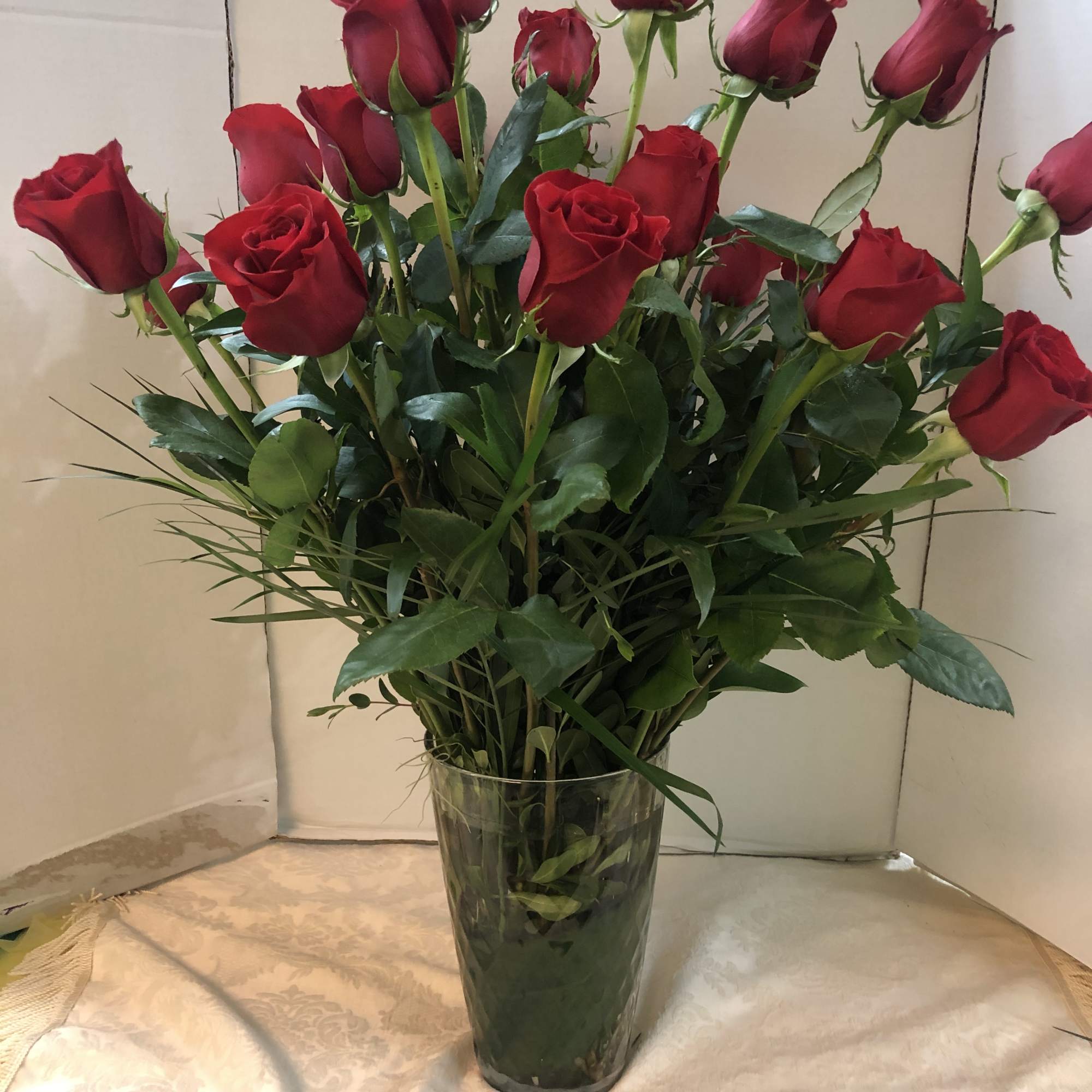 Tall bouquet of red roses in a clear glass vase