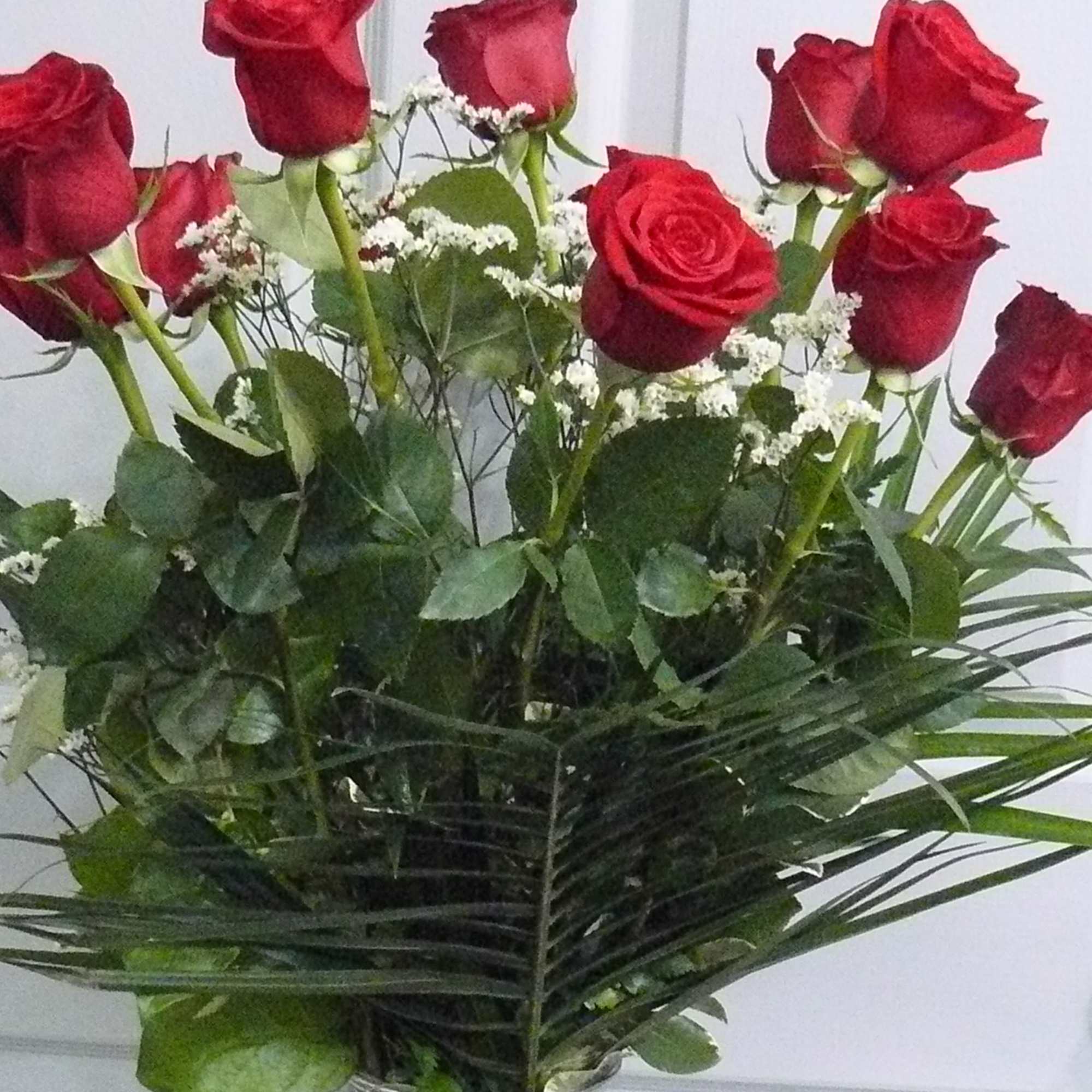 Red roses in a clear glass vase with white filler flowers