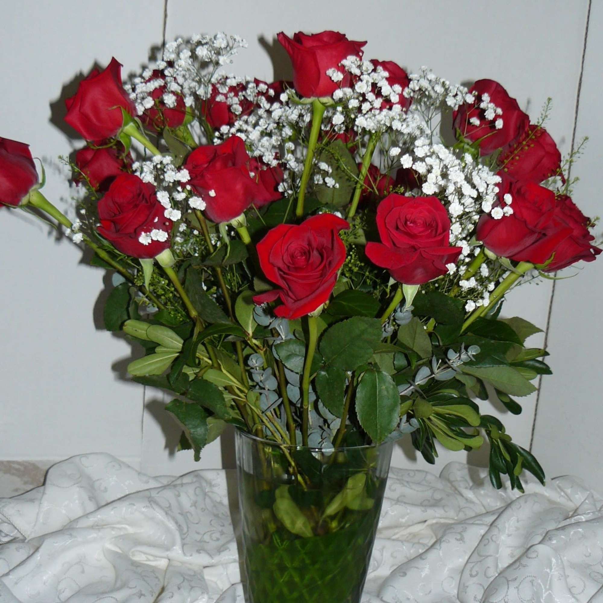 Bouquet of red roses and white baby's breath in a clear glass vase