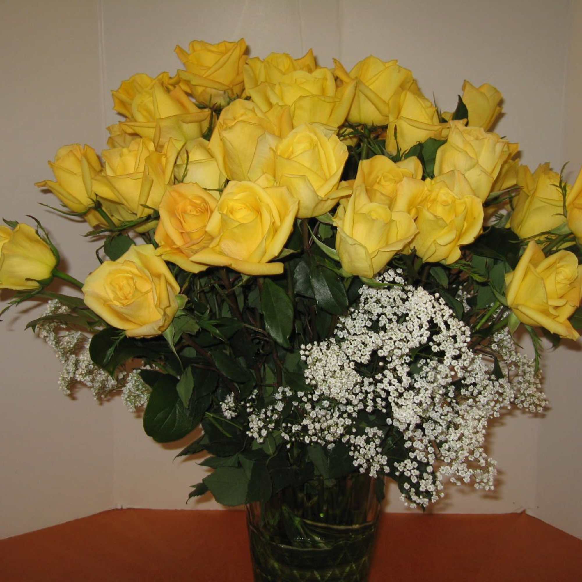 Bouquet of yellow roses with white filler flowers in a glass vase
