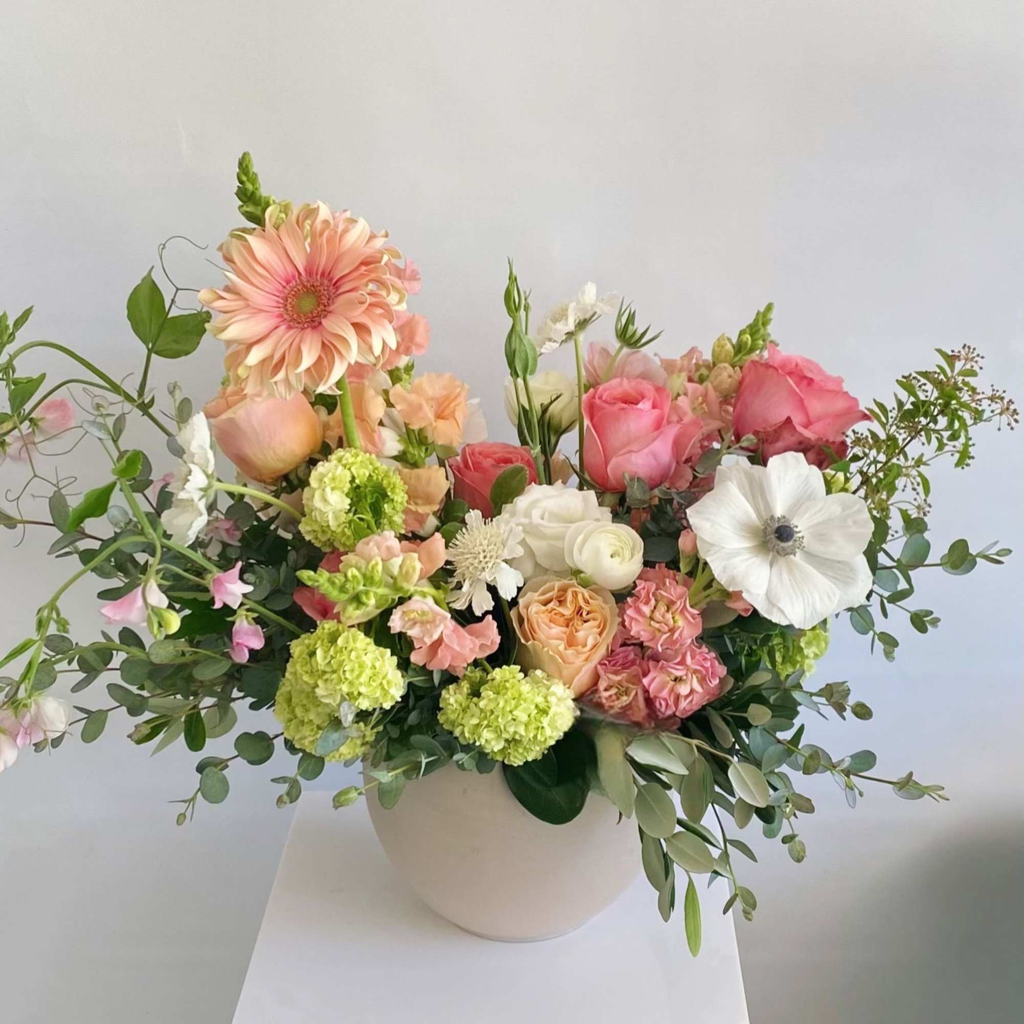 Mixed bouquet in a white vase with pink, peach, and white flowers