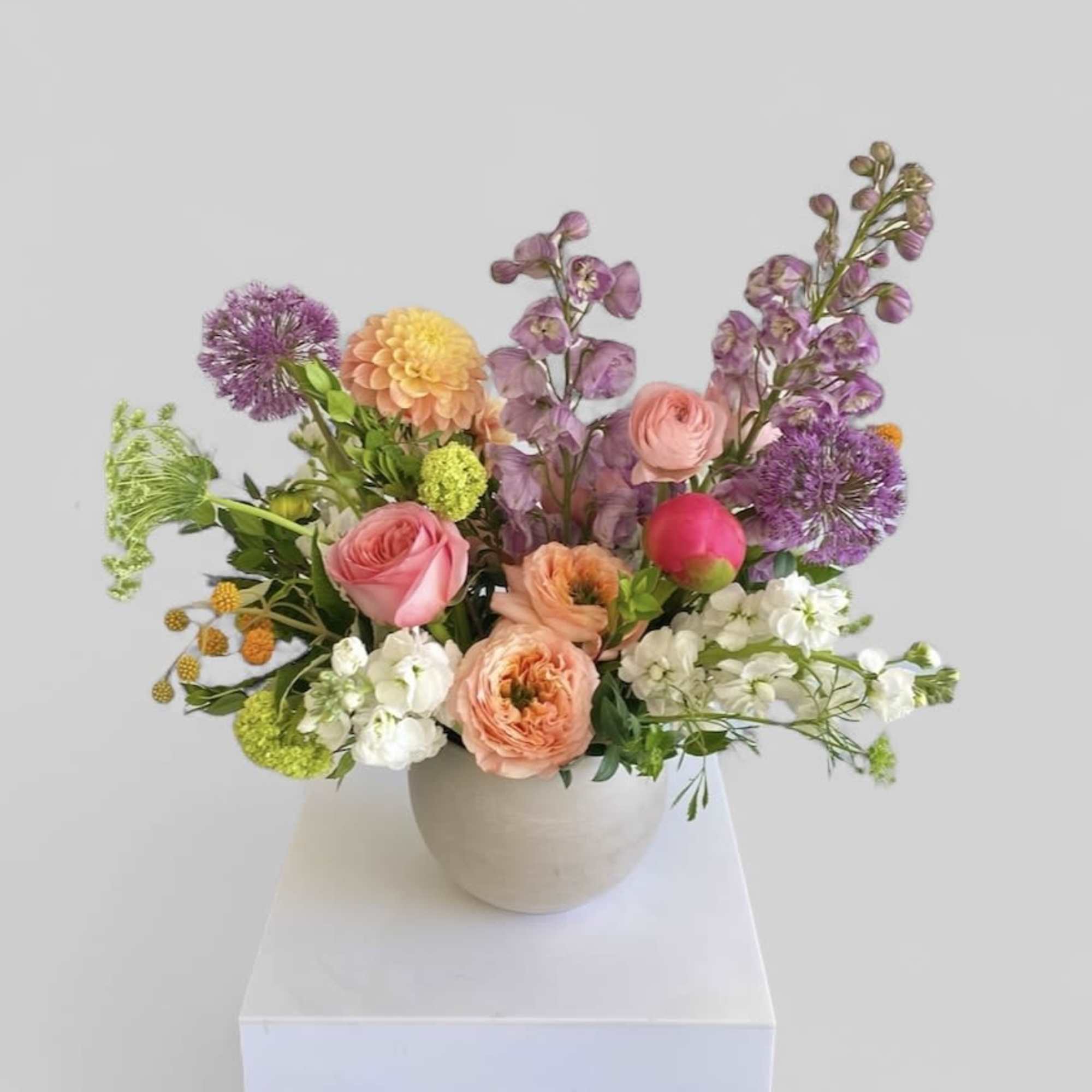 Mixed bouquet in a beige vase with pink, purple, peach, and white flowers