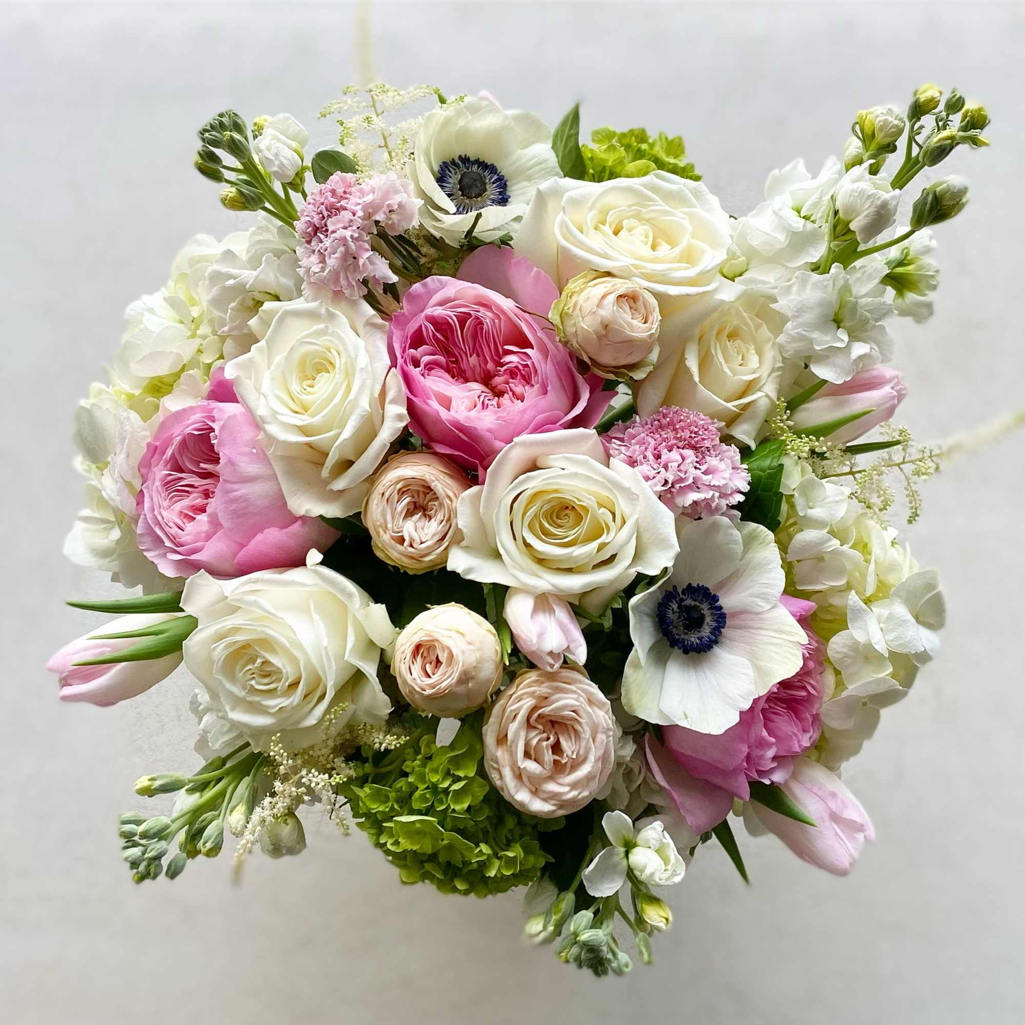 Round bouquet of pink and white roses with white anemones