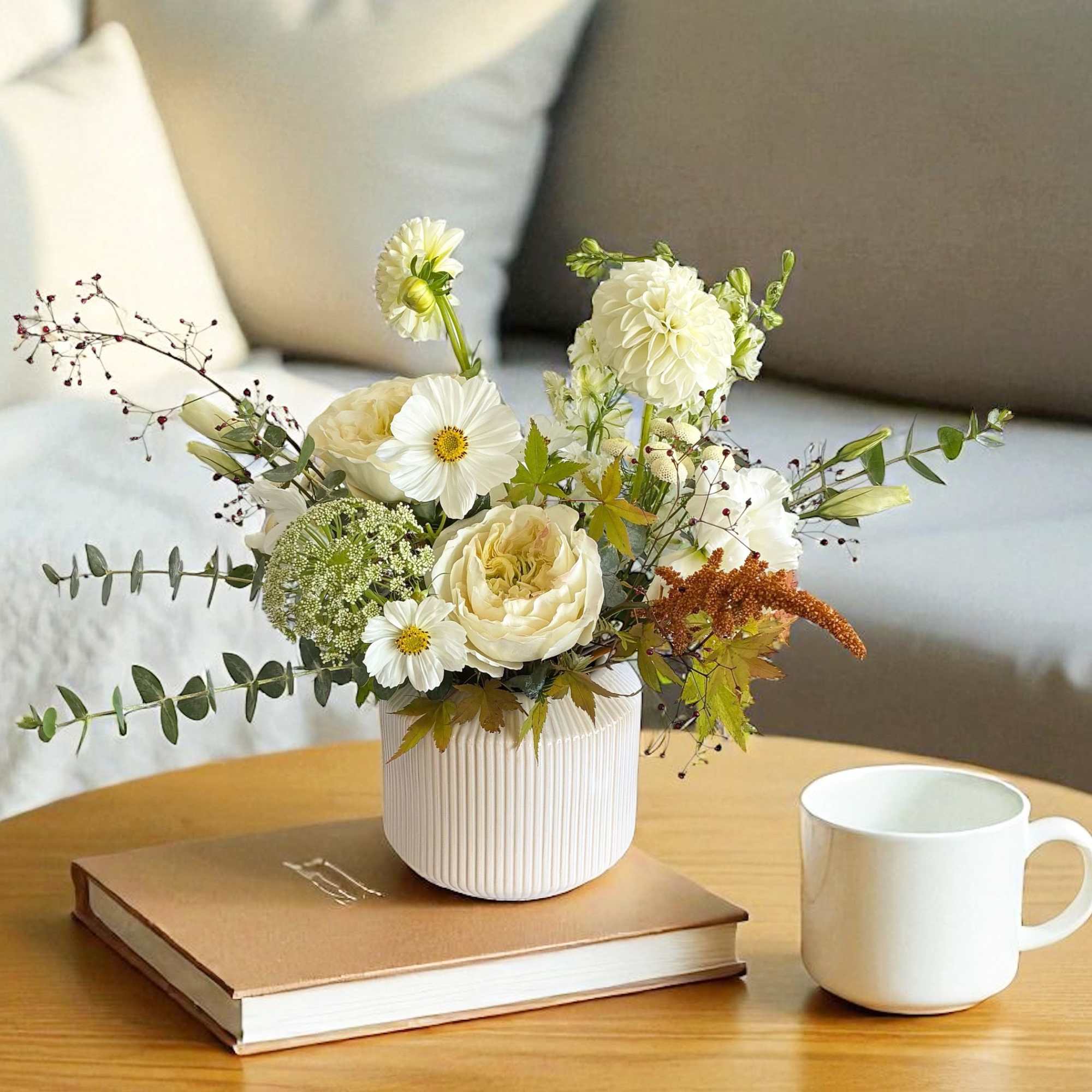 White and cream flower arrangement in a ribbed vase on a table
