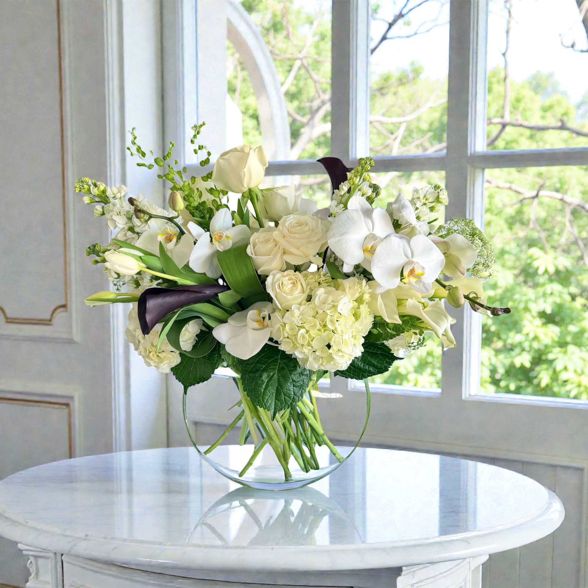 White floral bouquet in a clear glass vase on a round table