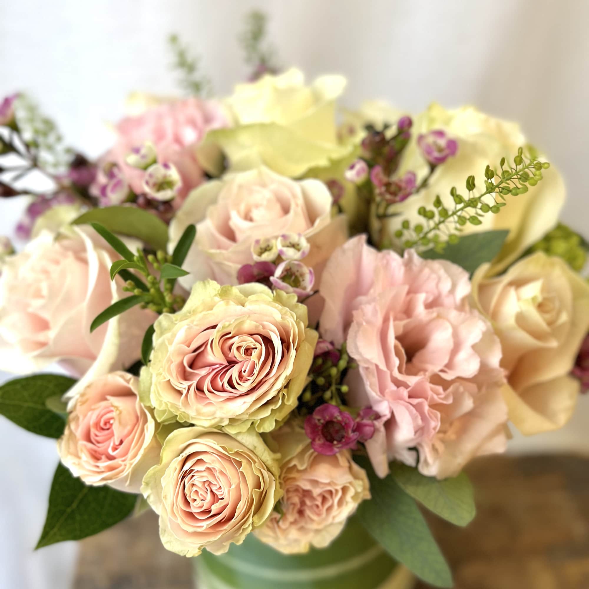 Pastel roses and ruffled blooms arranged in a striped vase