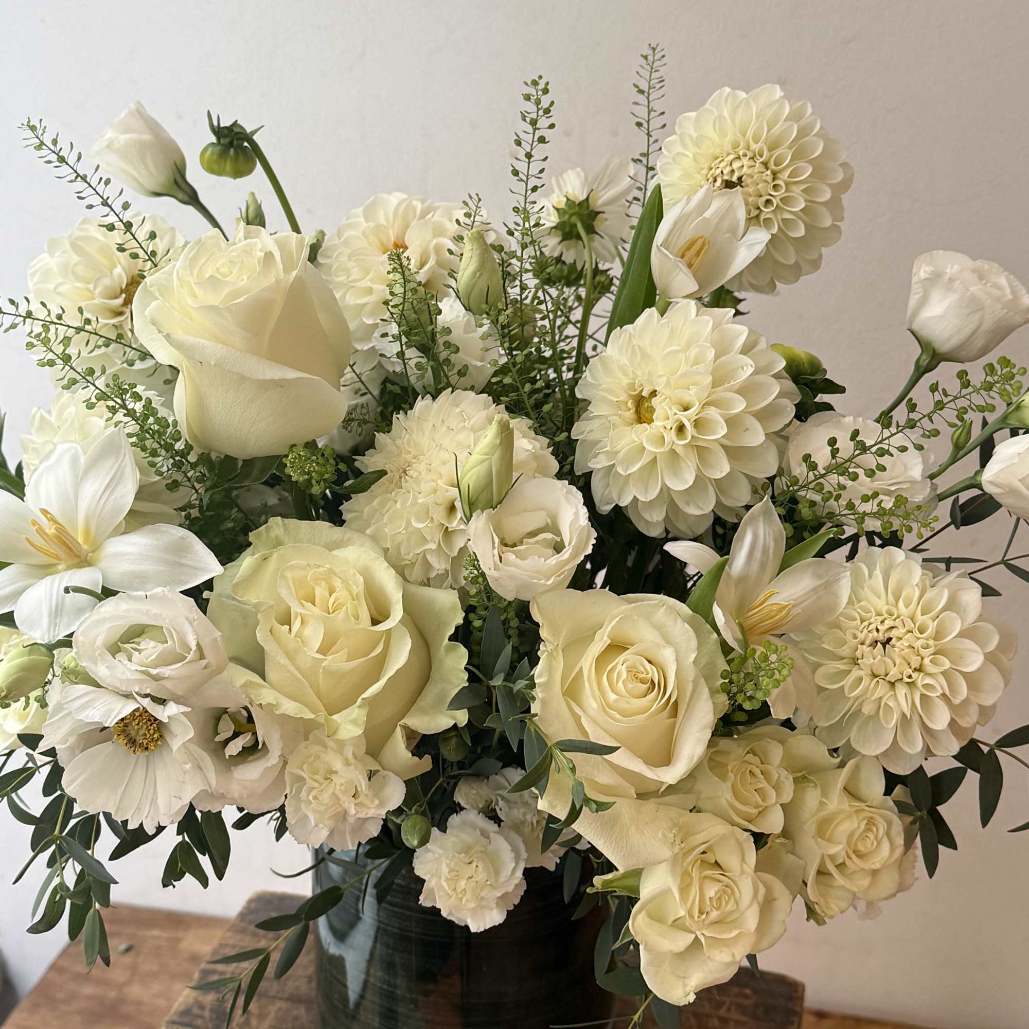 Creamy white bouquet of roses, dahlias, and calla lilies in a dark vase