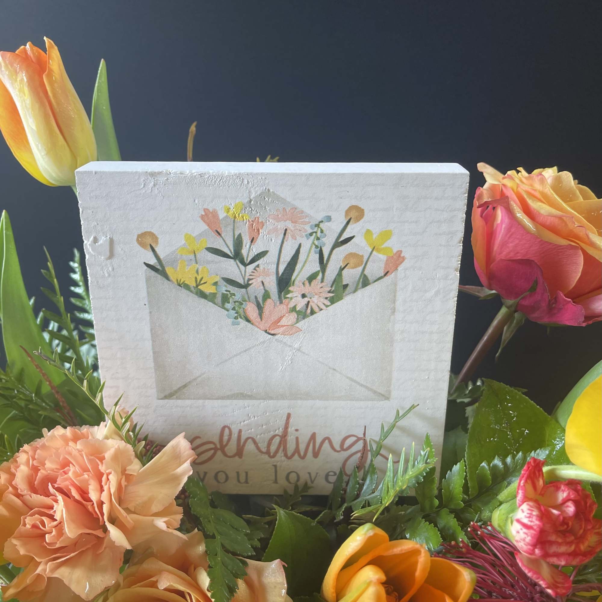 Mixed bouquet with roses, tulips, and carnations around a sympathy card