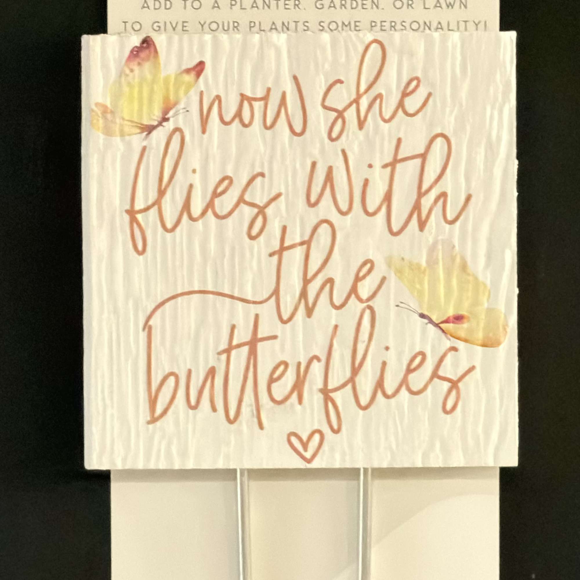 Two plant stake signs with butterfly designs and handwritten text