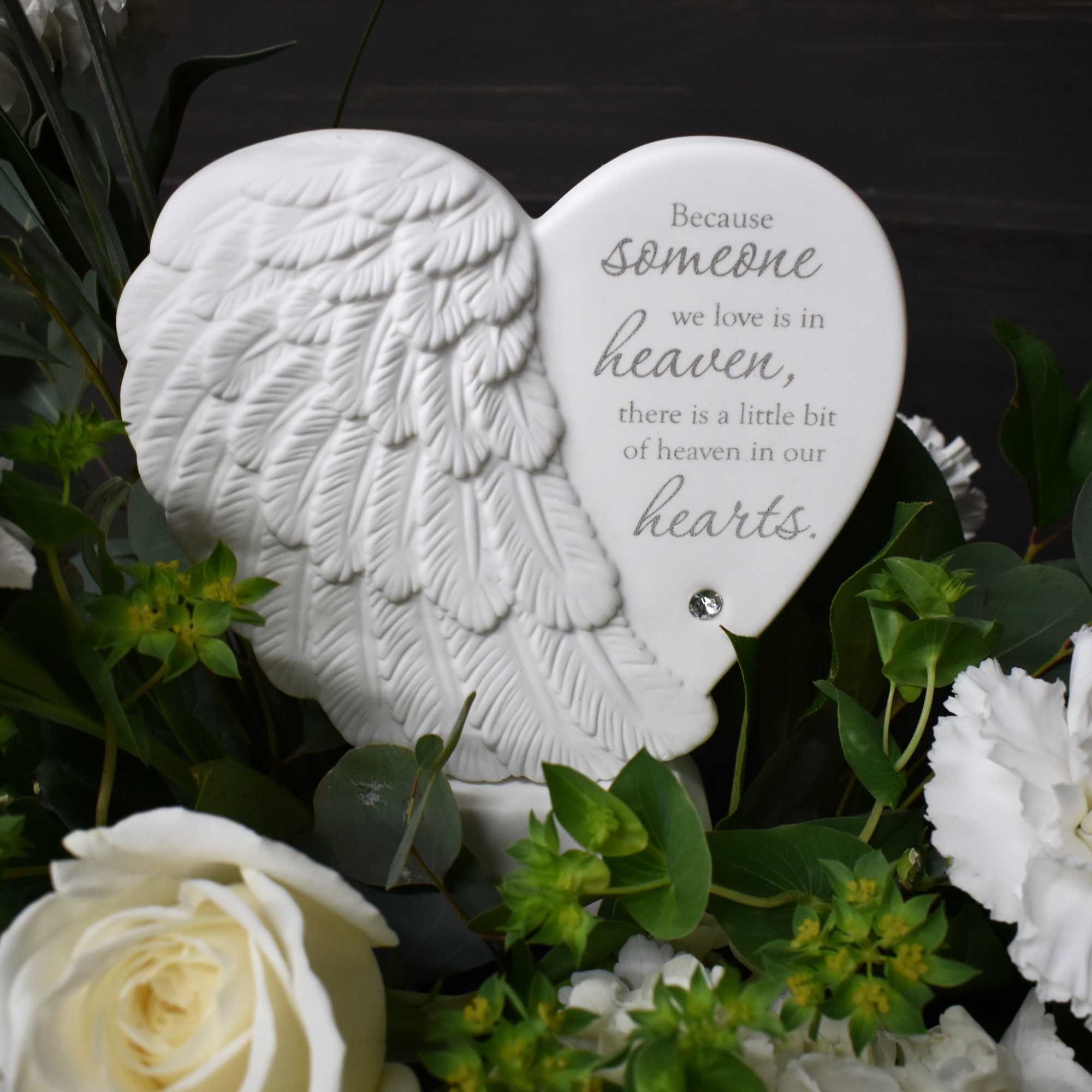 Heart-shaped memorial plaque surrounded by white flowers and greenery