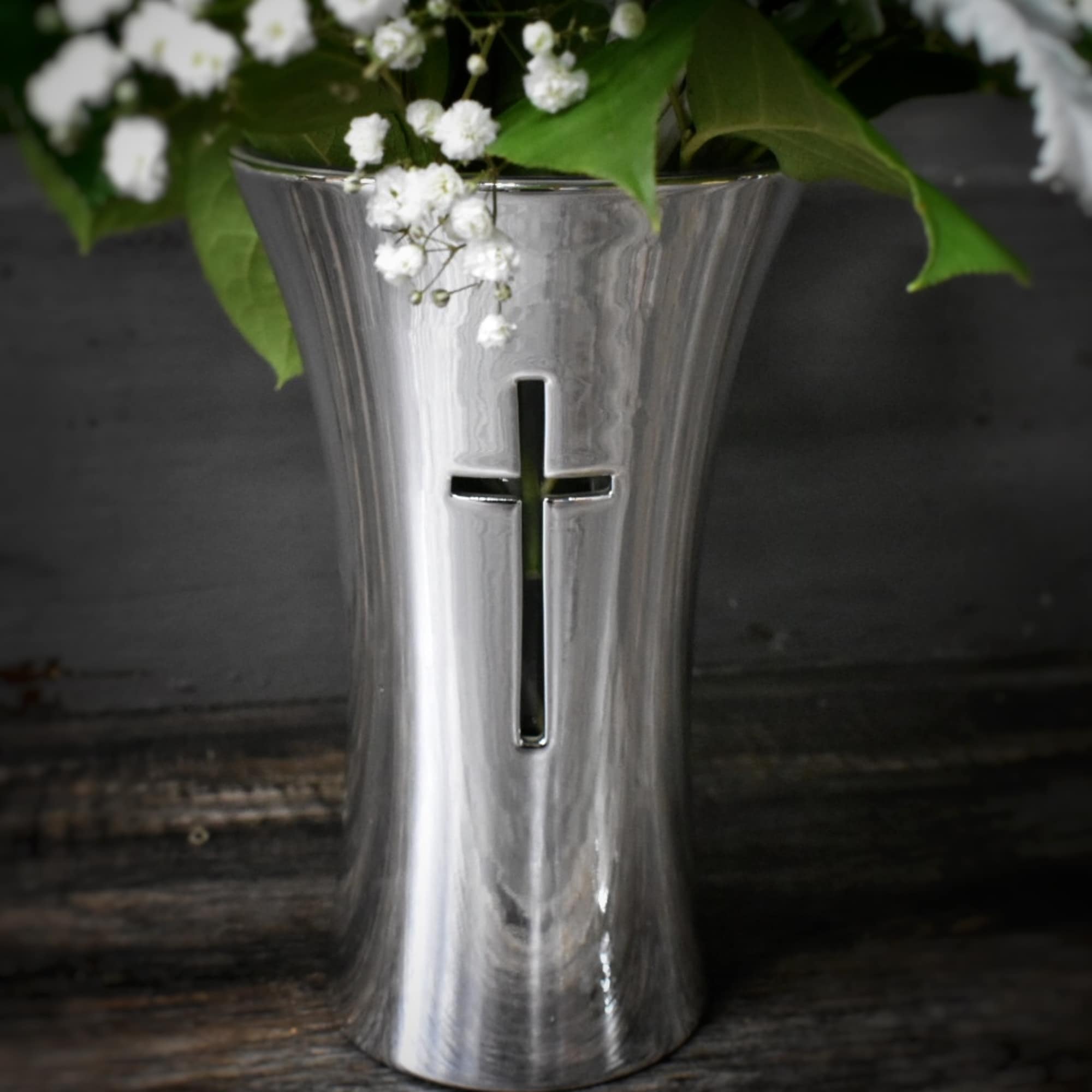 White flowers in a silver vase with a cross cutout