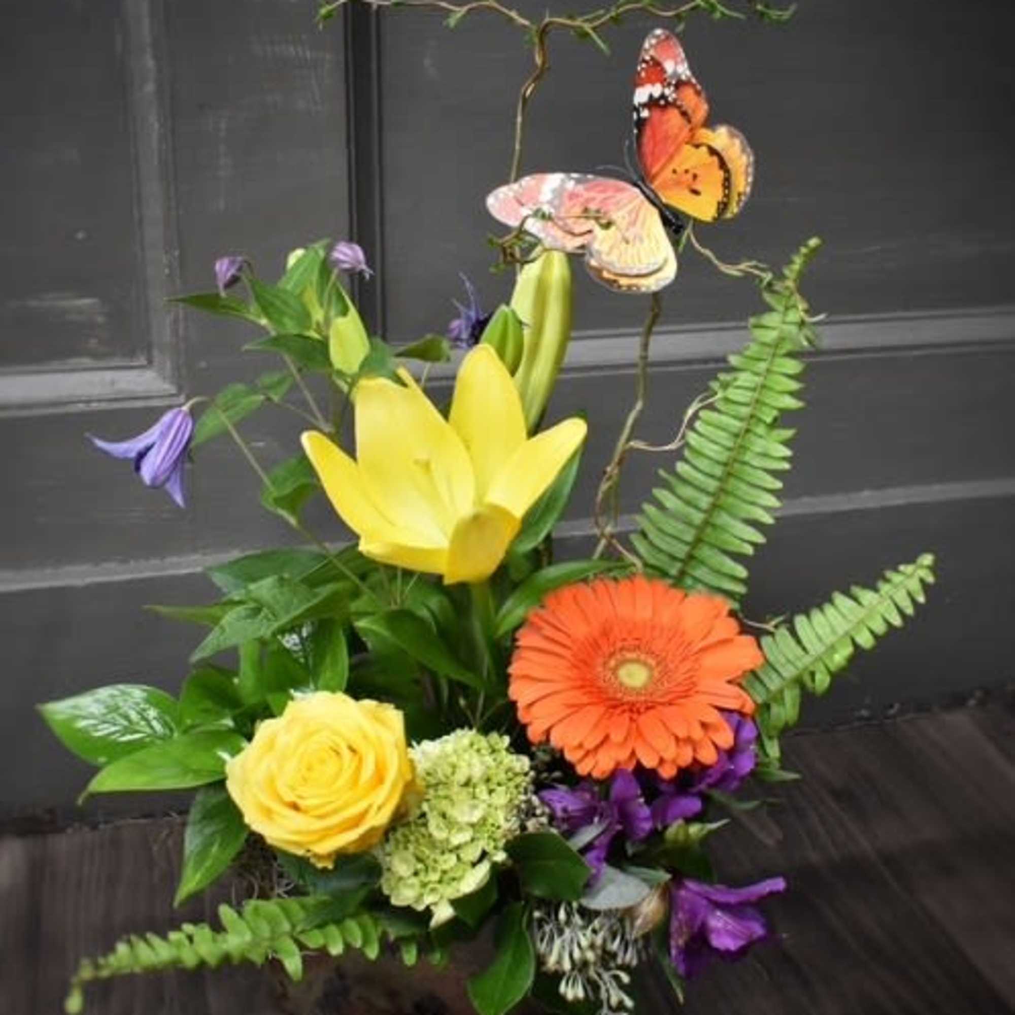 Bright mixed flower arrangement with butterflies and fern accents