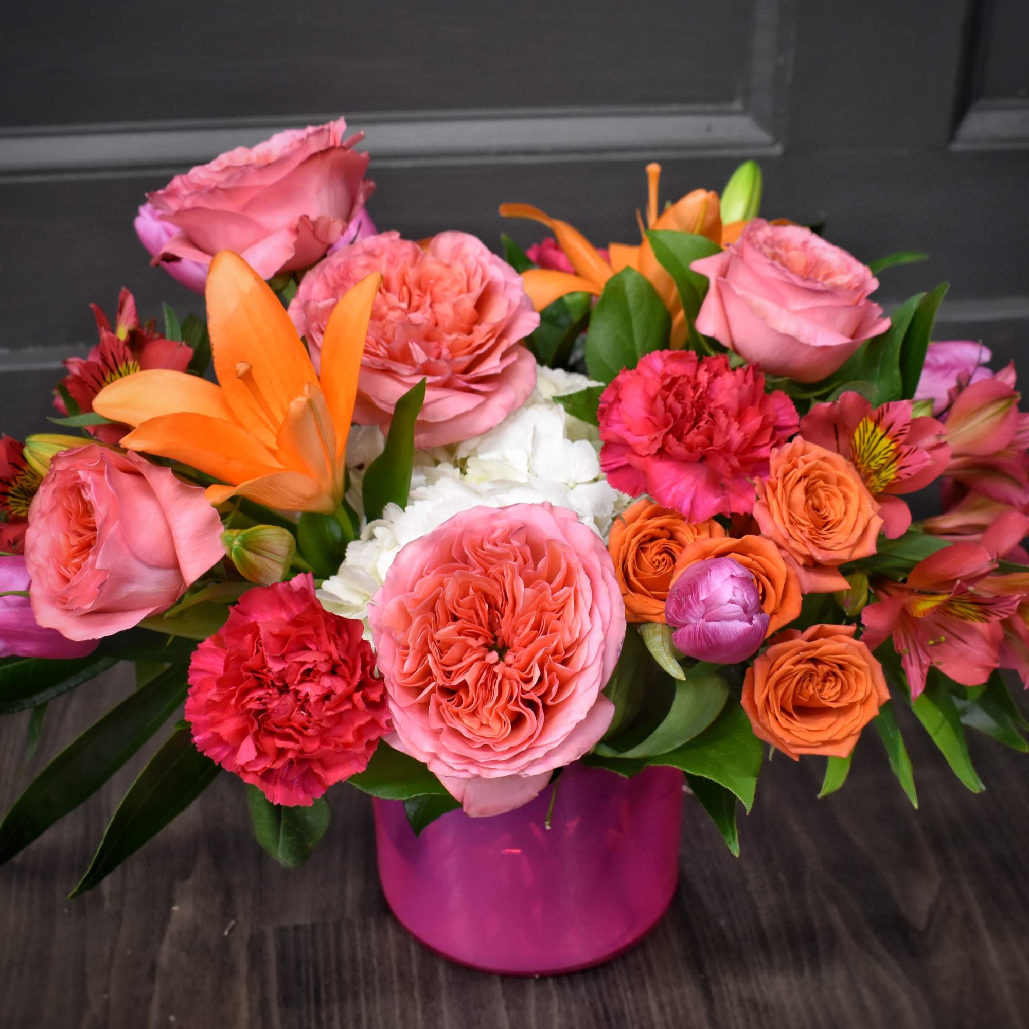 Mixed bouquet of pink and orange flowers in a pink vase