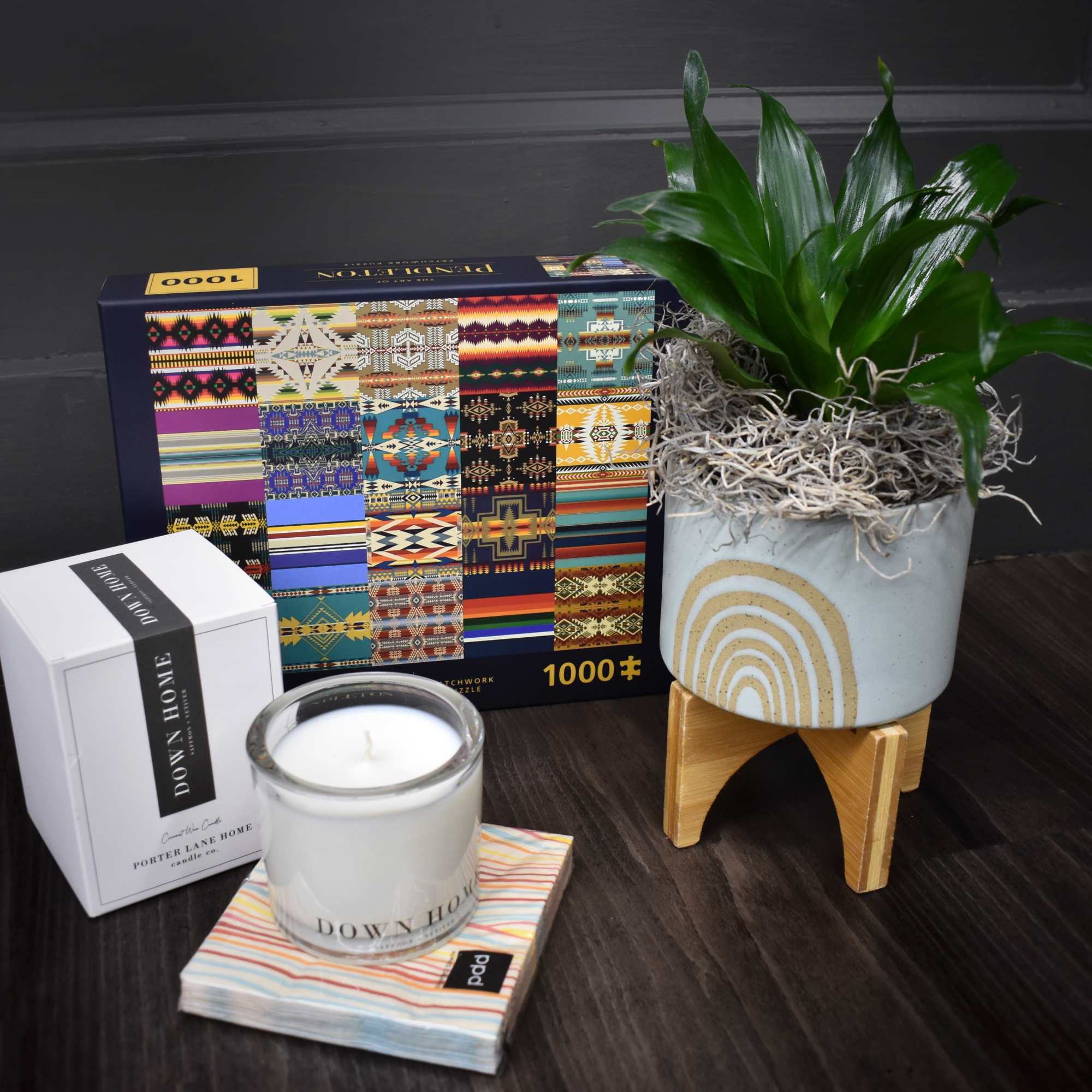 Potted green plant in a decorative ceramic pot beside a candle and gift box