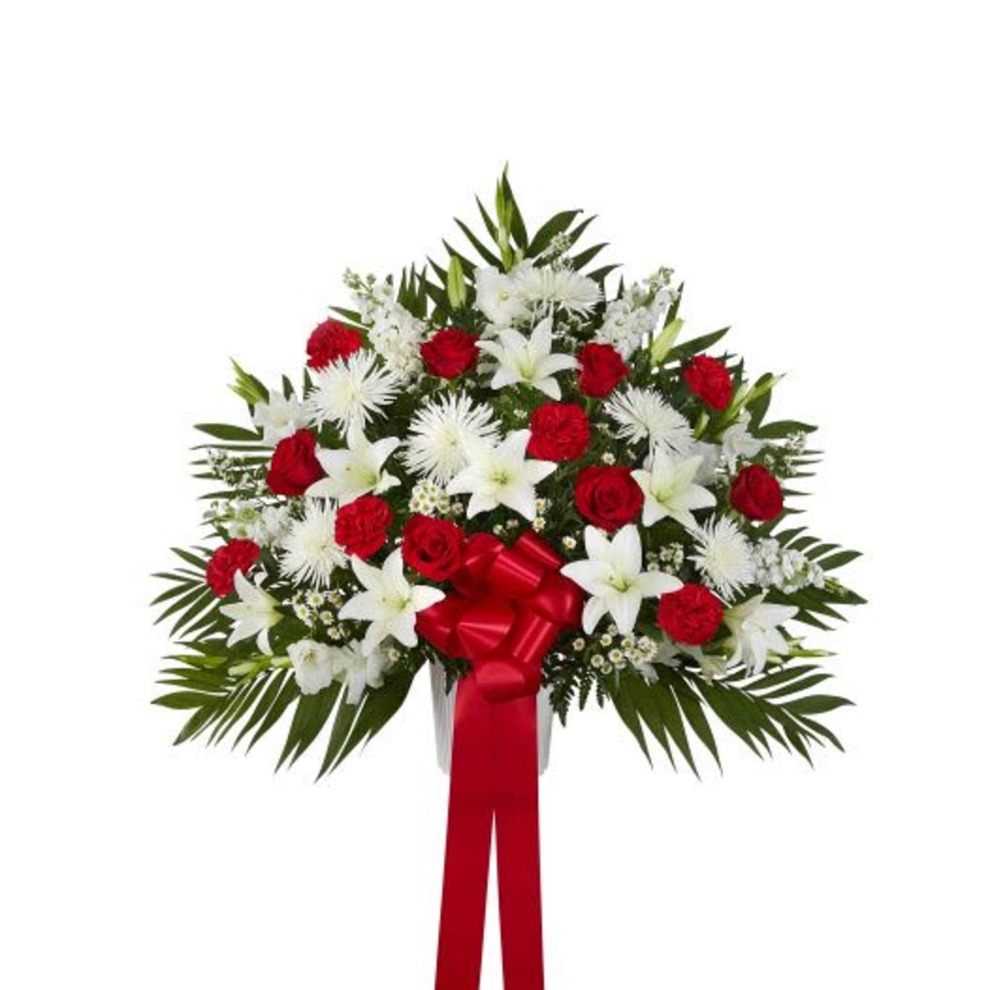Standing spray of red roses and white lilies with a red bow and ribbon.