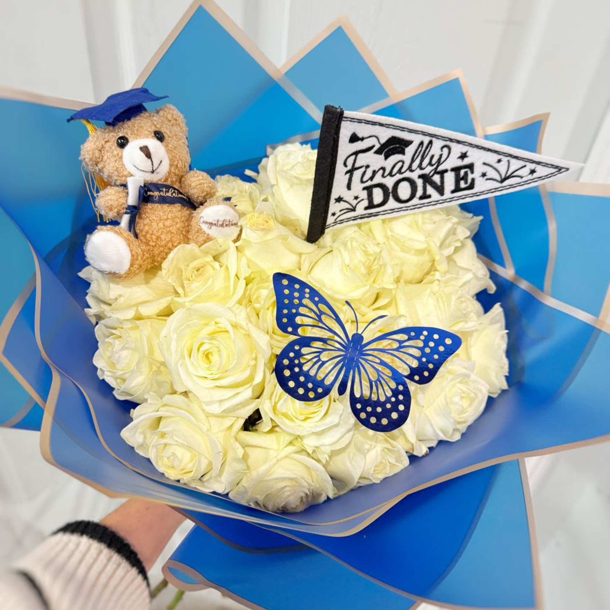 Bouquet of white roses with a teddy bear and graduation decorations