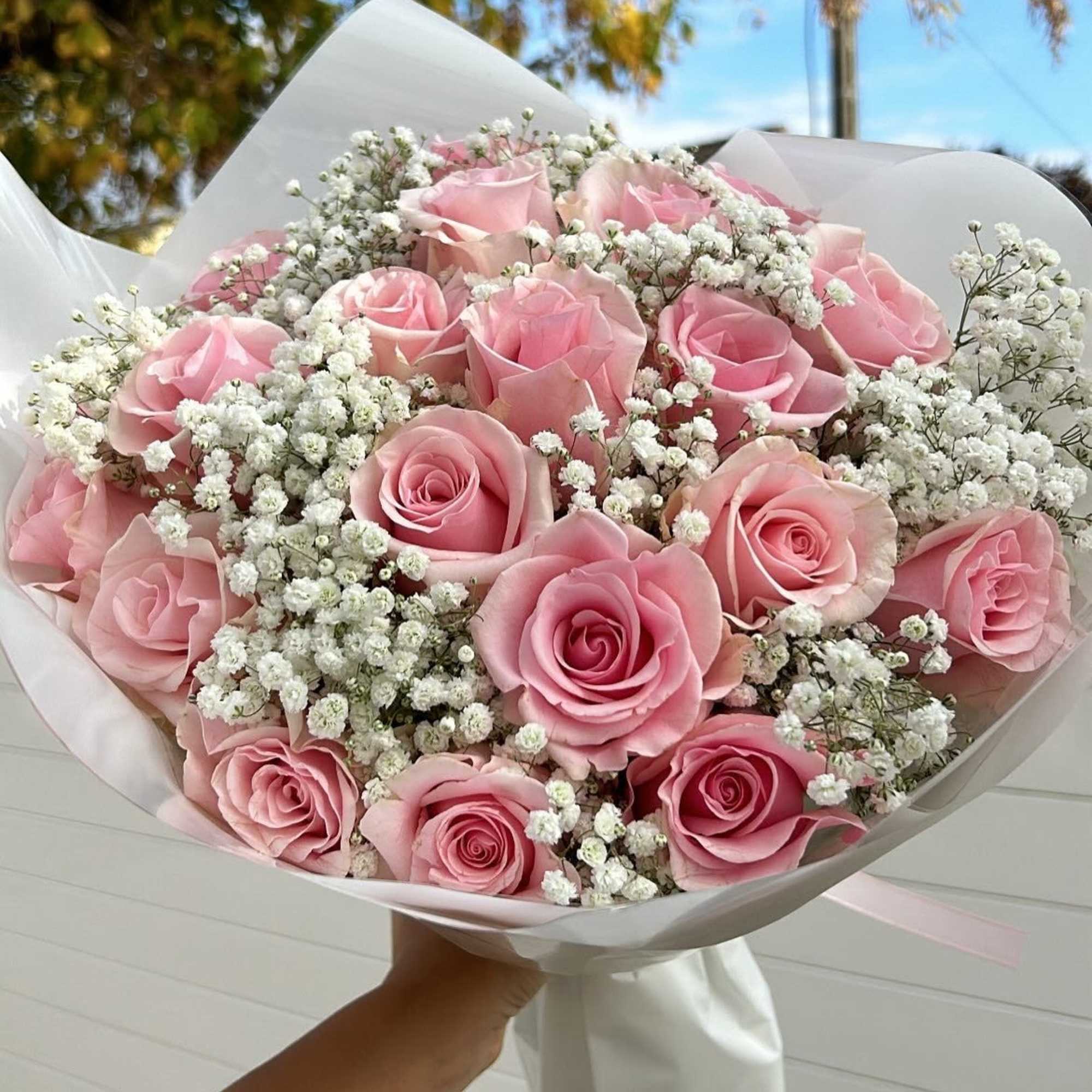 Bouquet of pink roses and white baby's breath wrapped in white paper