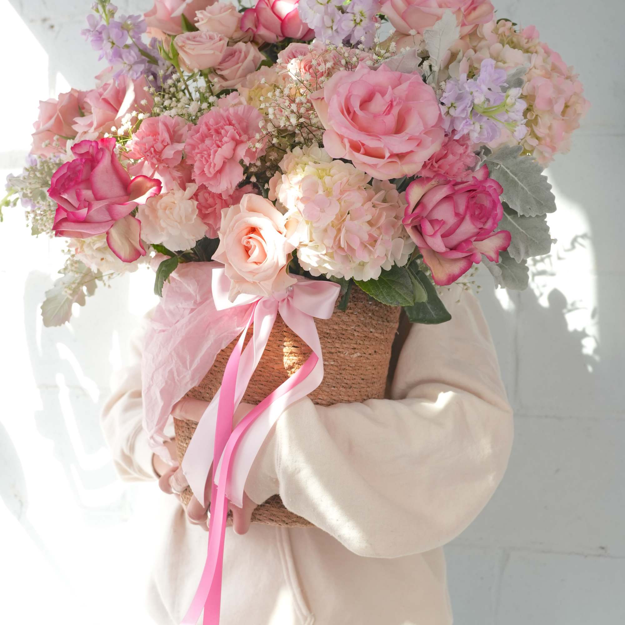 Large pink and white bouquet in a woven basket with ribbon