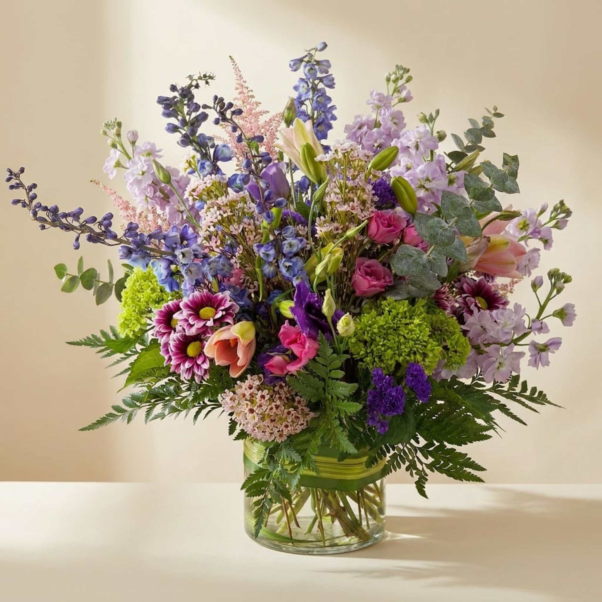 Mixed bouquet of purple, pink, and green flowers in a glass vase