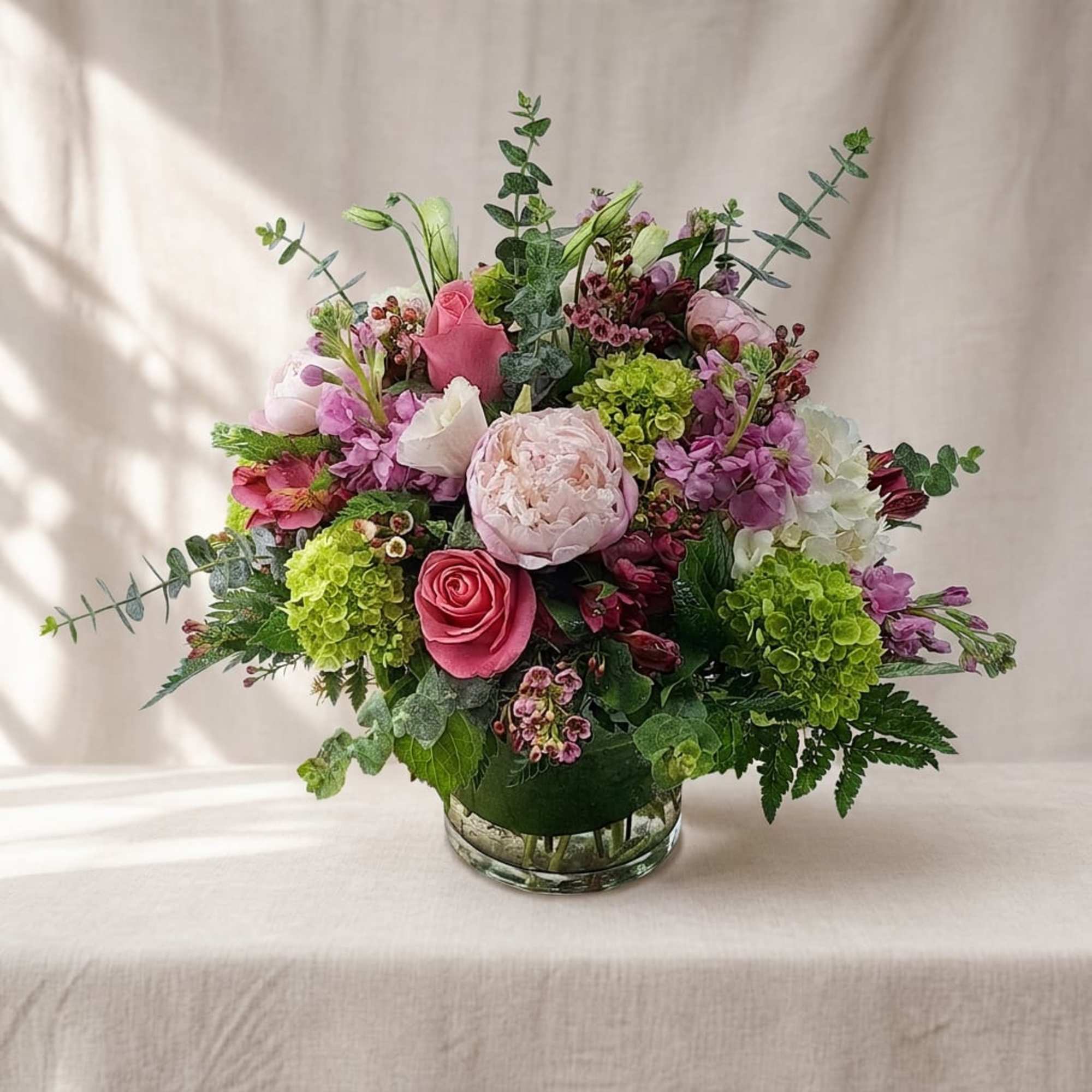 Pink and purple mixed flower arrangement in a clear glass vase