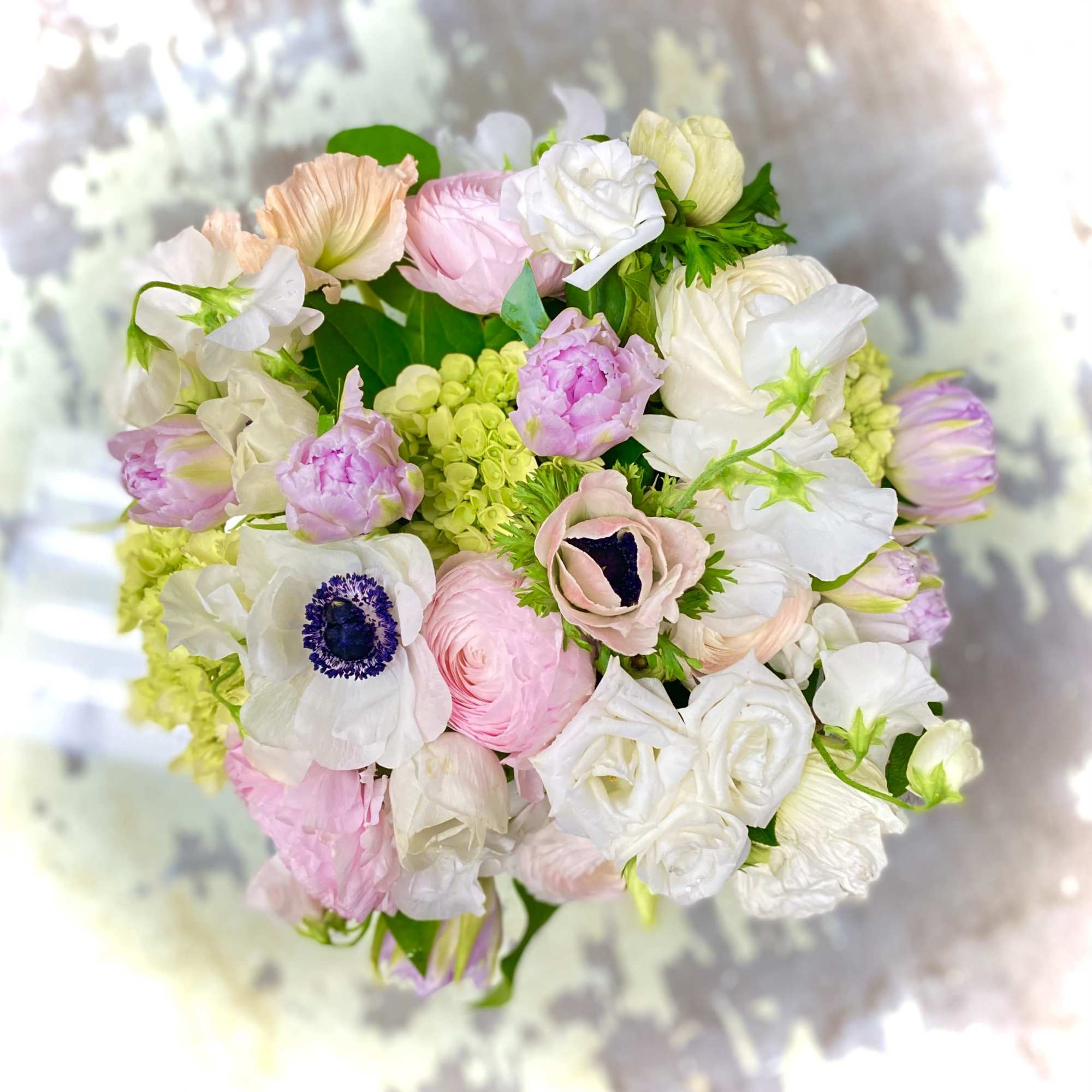Pastel bouquet of white, pink, and peach flowers with green accents