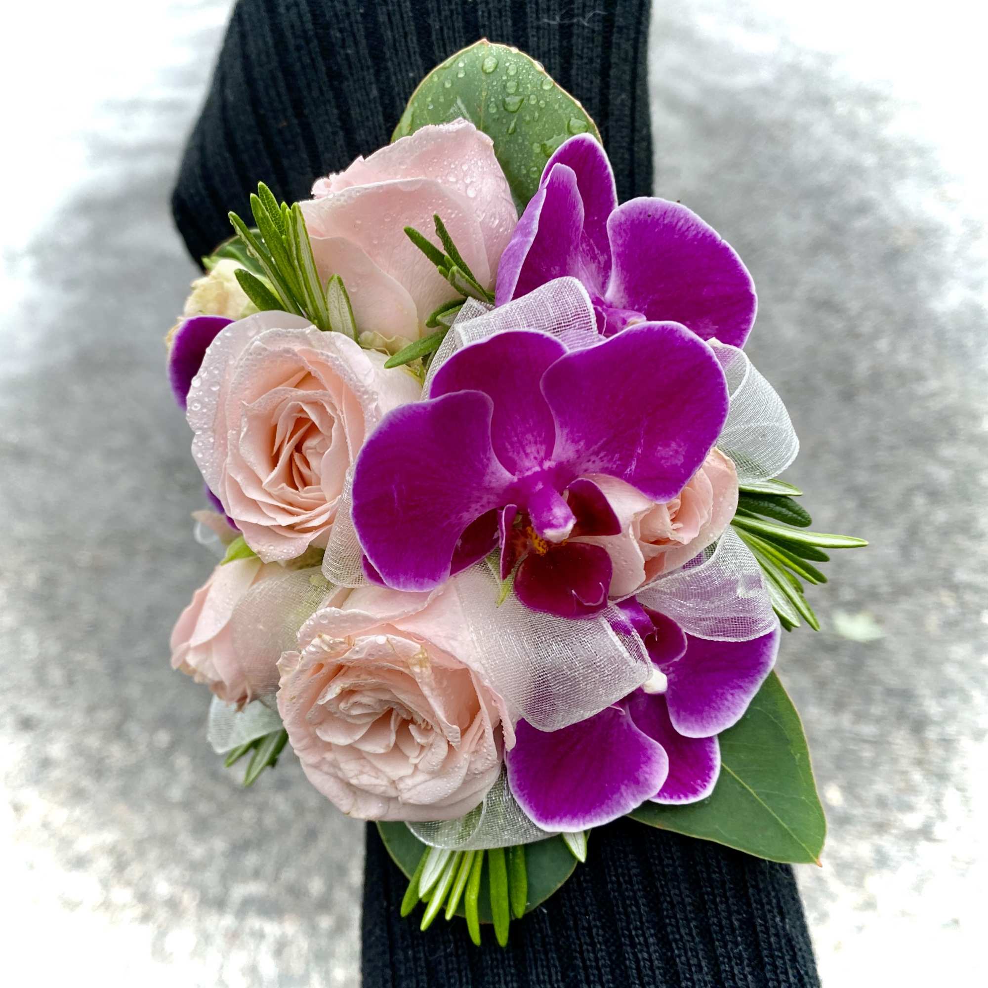 Pink roses and purple orchids arranged as a wrist corsage