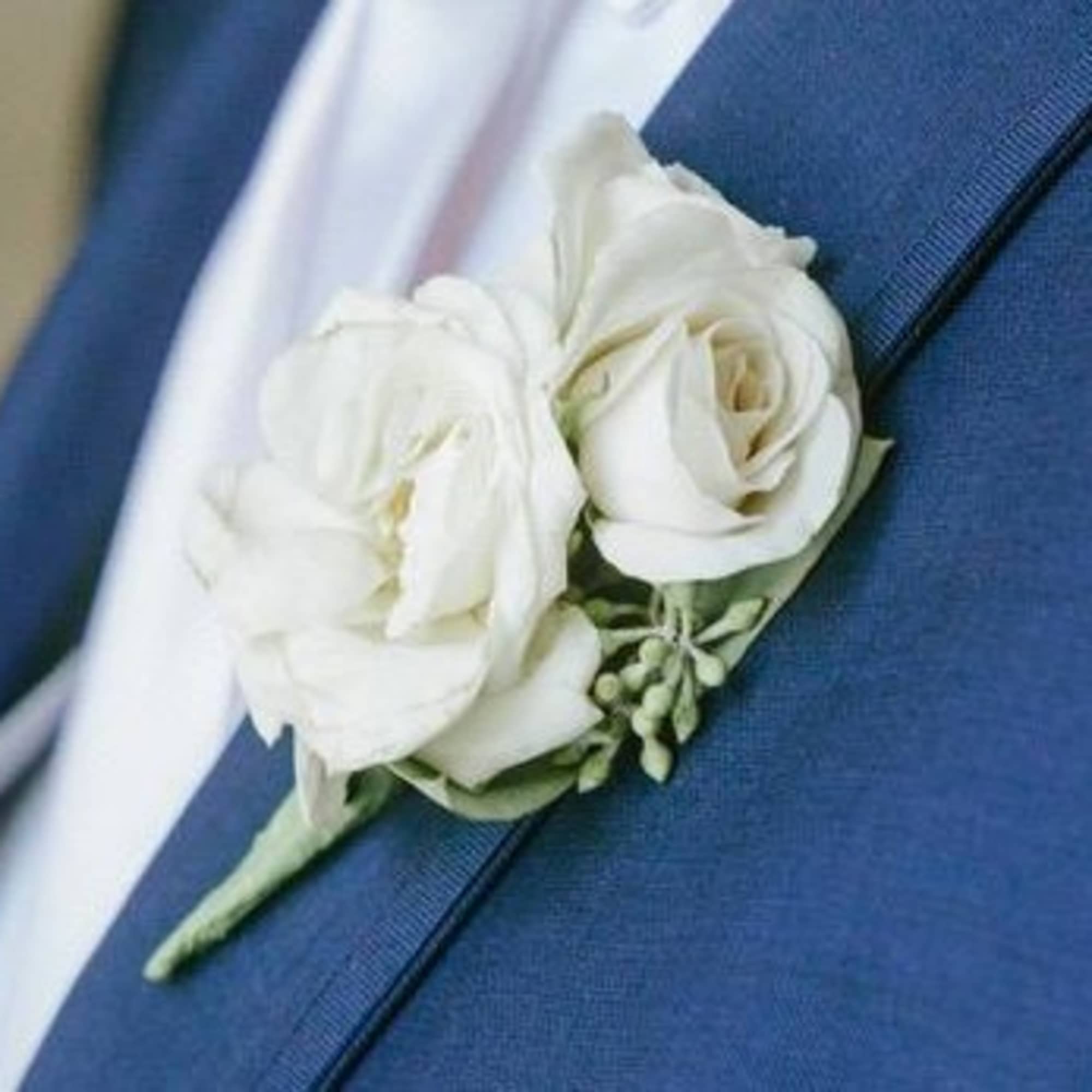 White rose boutonniere pinned to a blue suit jacket