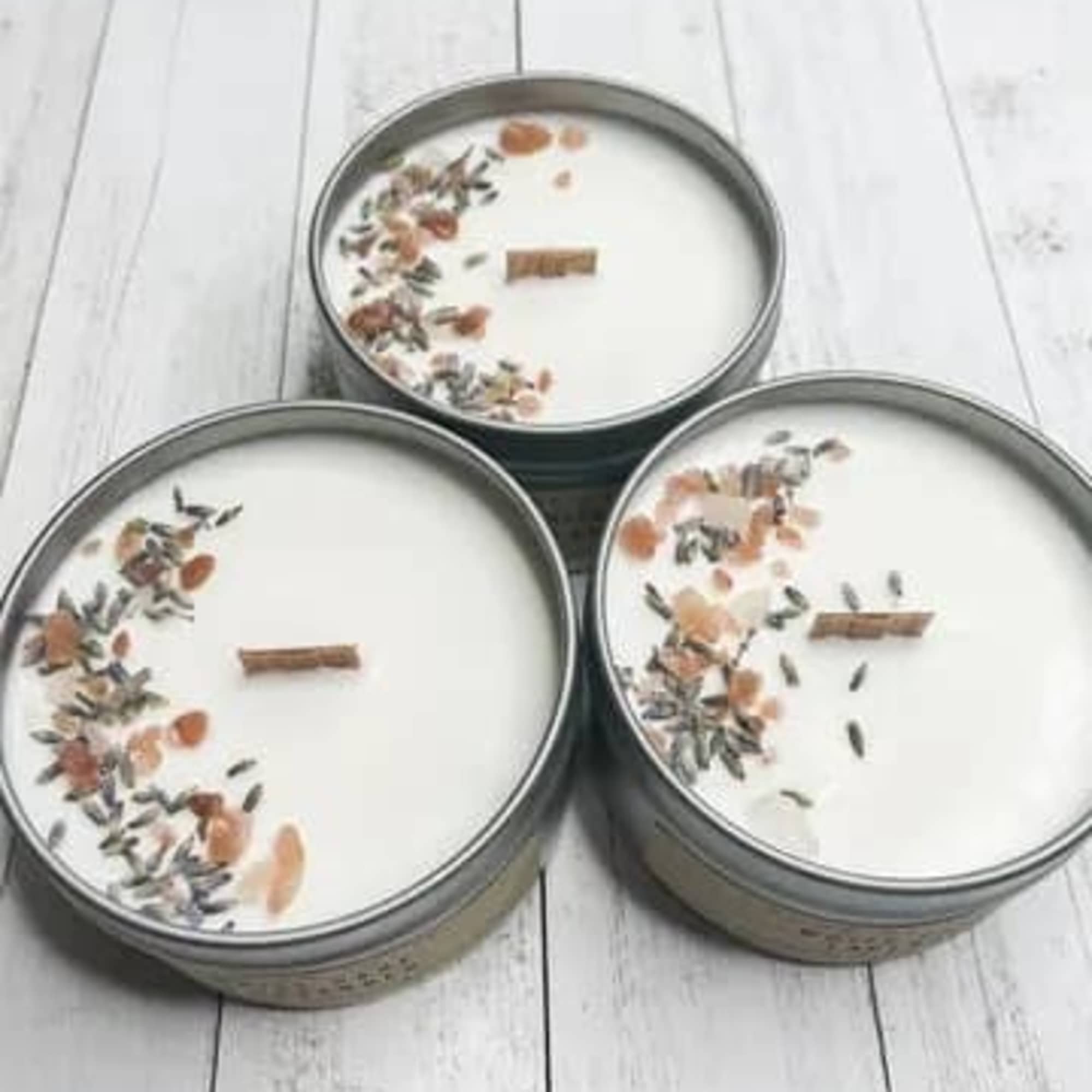 Three round tin candles with white wax and floral decoration