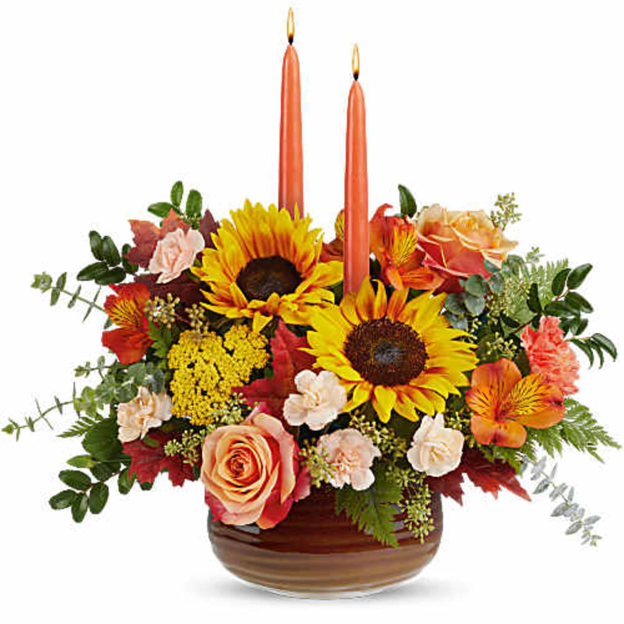 Autumn floral arrangement with two orange candles in a low bowl vase