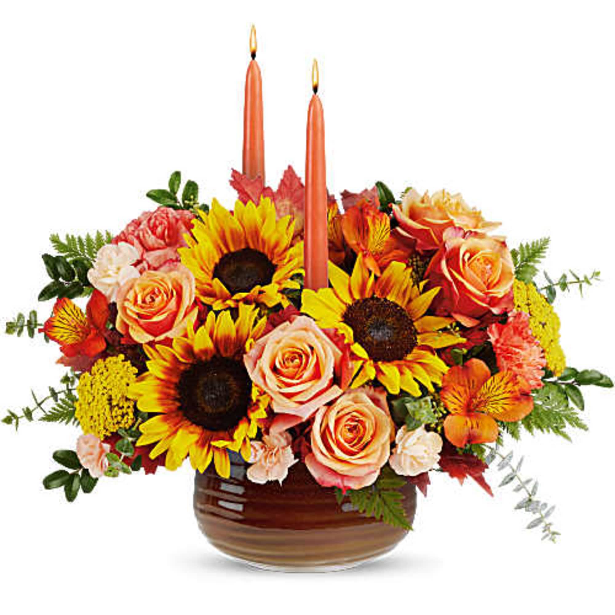 Sunflower and rose arrangement in a brown bowl with two orange candles
