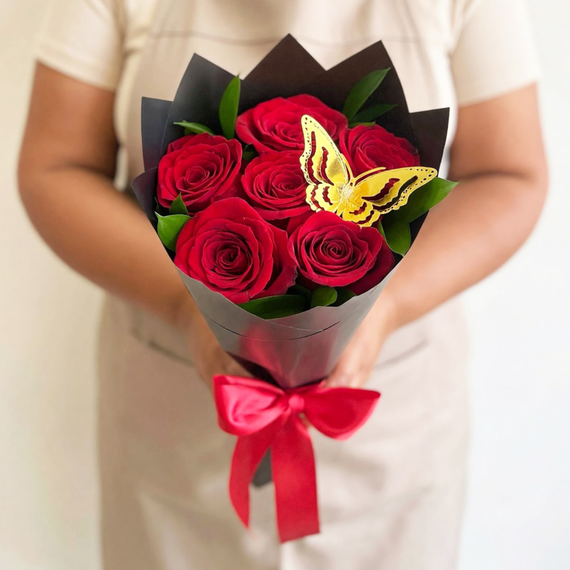 Bouquet of red roses wrapped in black paper with a red ribbon and butterfly decoration