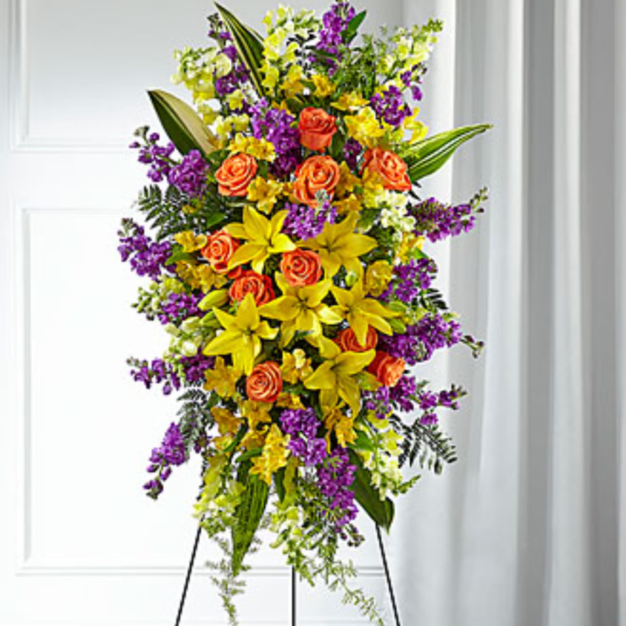 Tall standing spray with orange roses, yellow lilies, and purple flowers