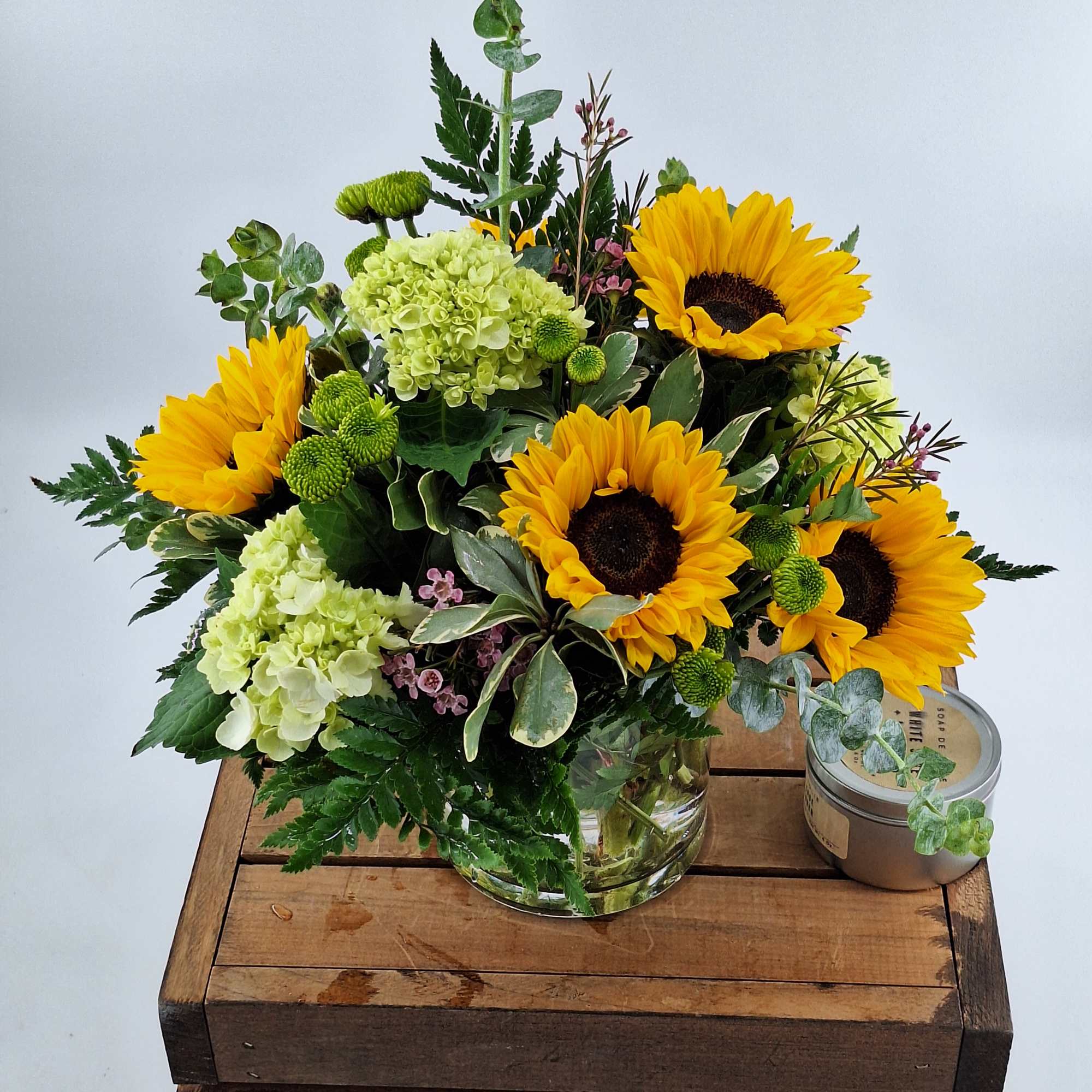 Bouquet of sunflowers and pale green hydrangeas in a glass vase