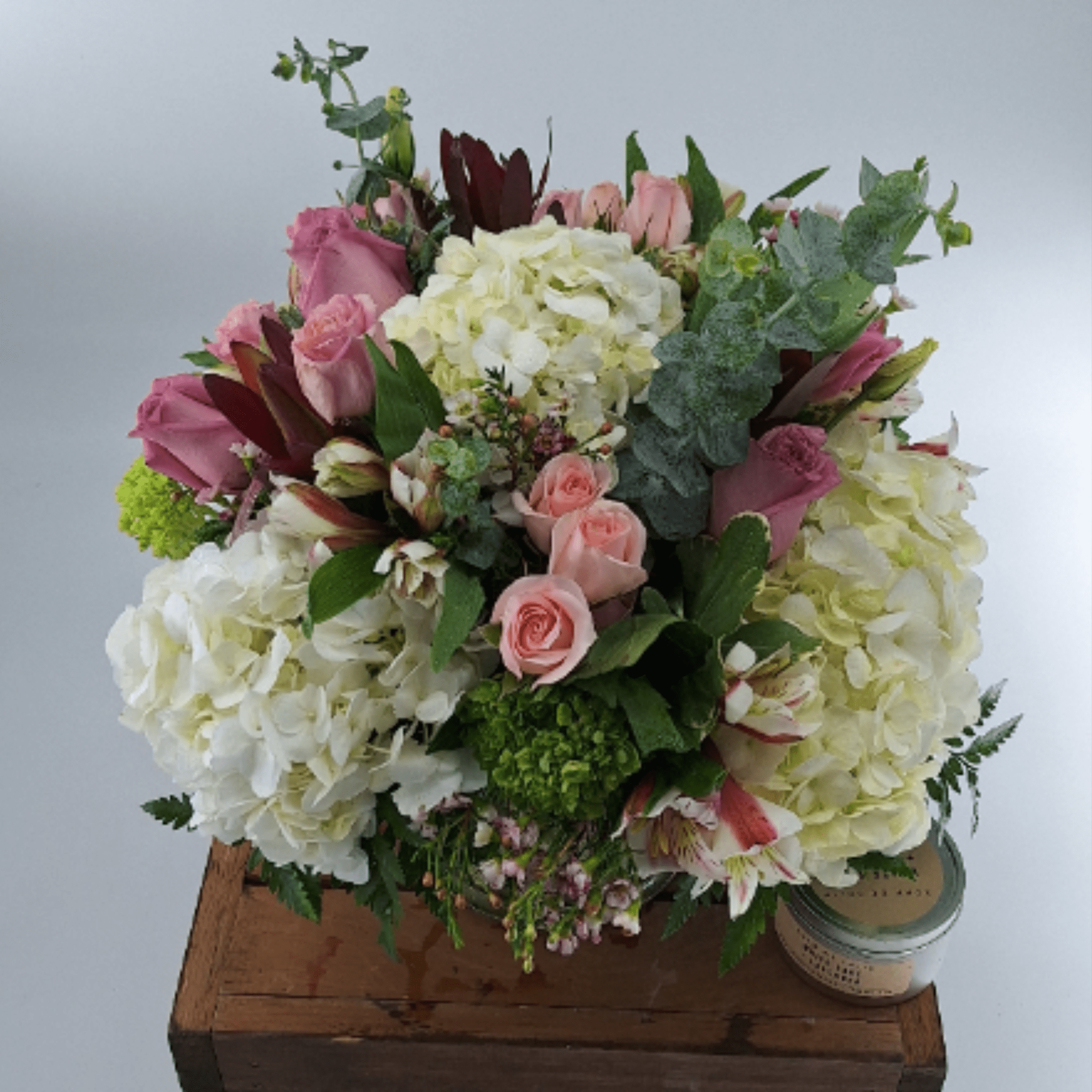 Pink roses and white hydrangeas arranged in a low bouquet with greenery