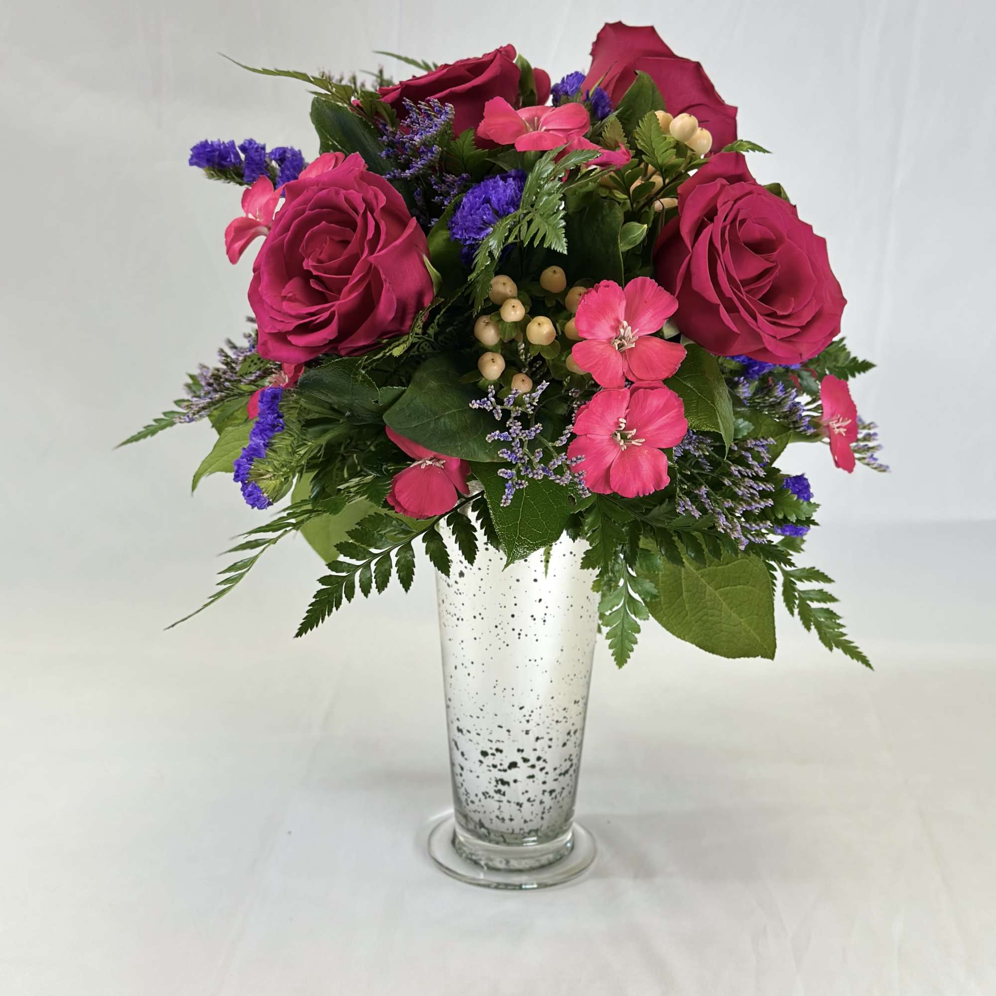 Pink roses and mixed blooms arranged in a clear vase