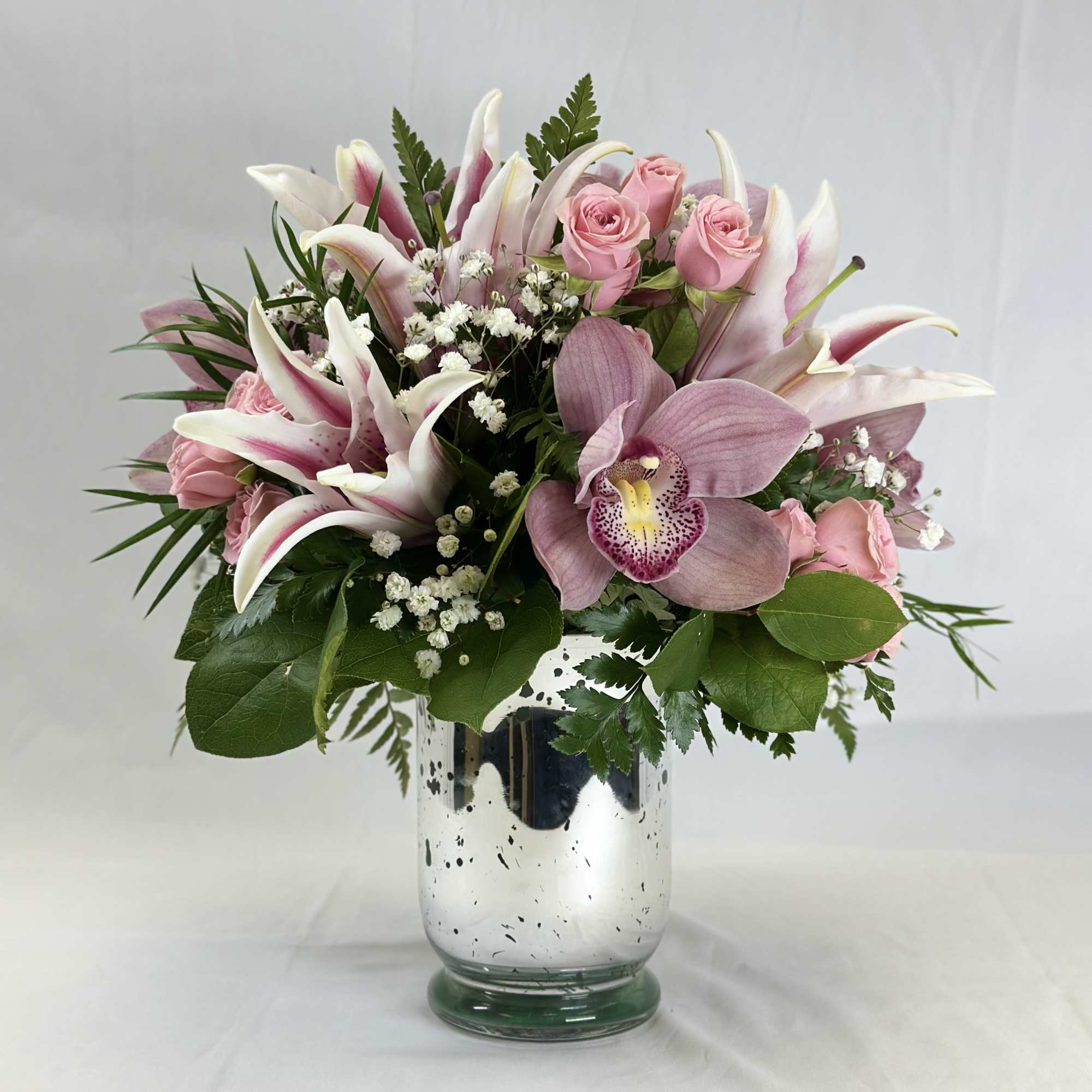 Pink roses and lilies arranged in a silver vase