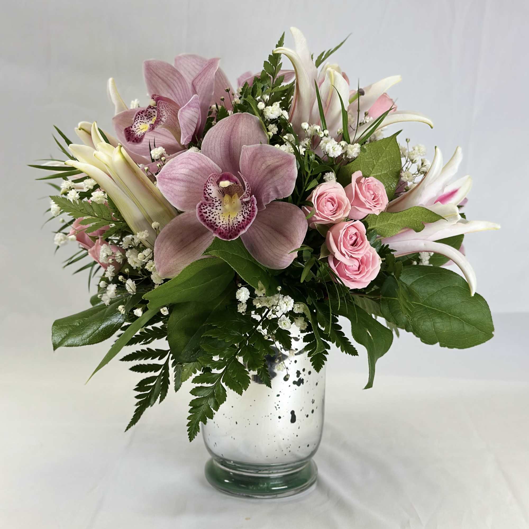 Pink orchids and roses arranged in a glass vase