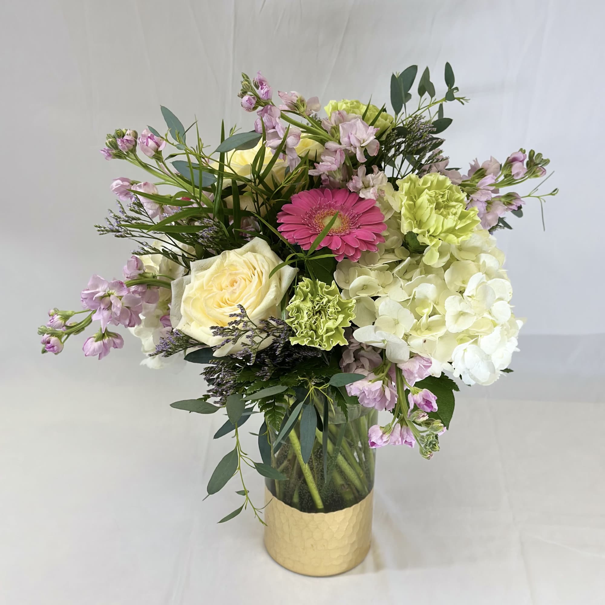 Mixed bouquet in a gold vase with pink, white, and green flowers