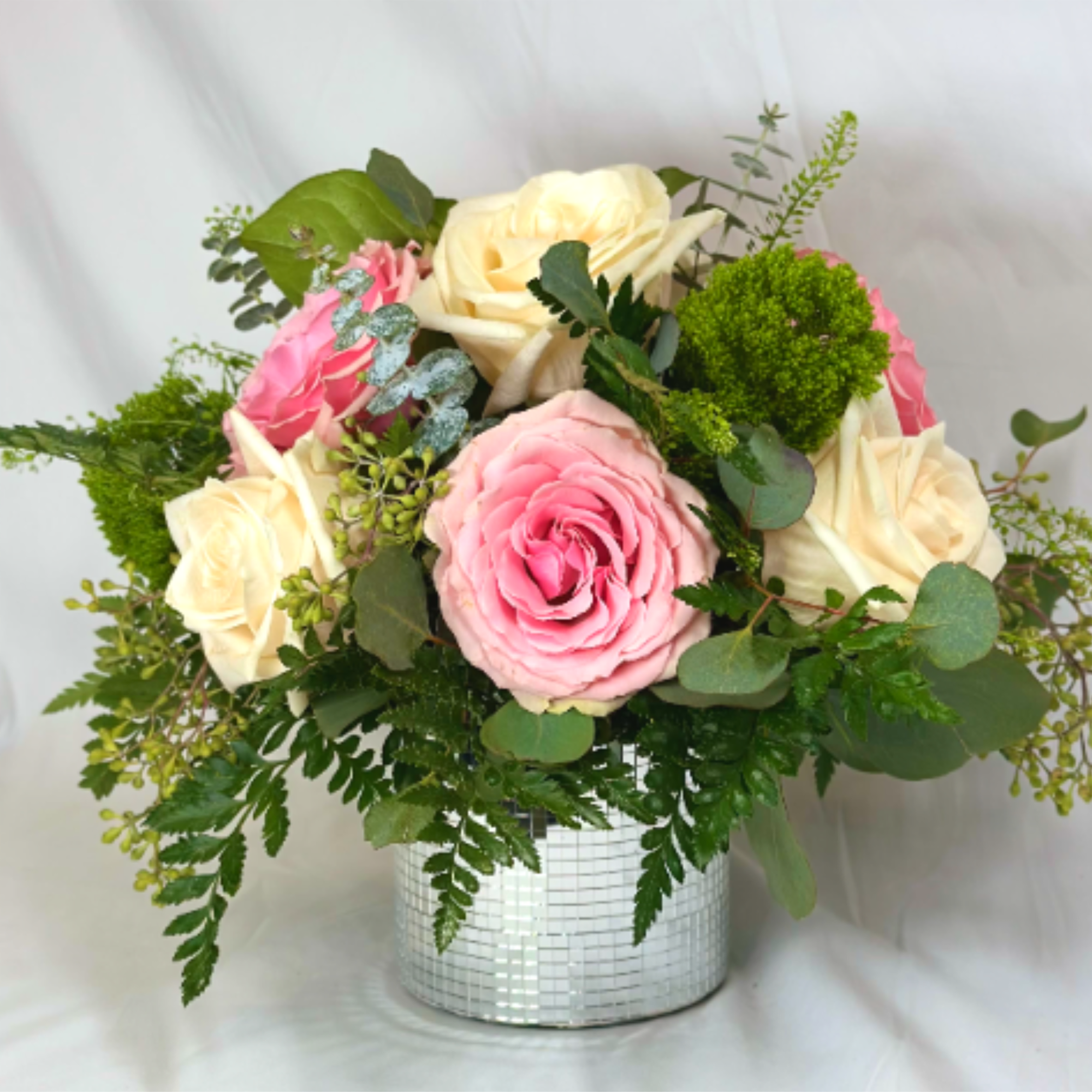 Pink and cream roses in a silver mosaic vase