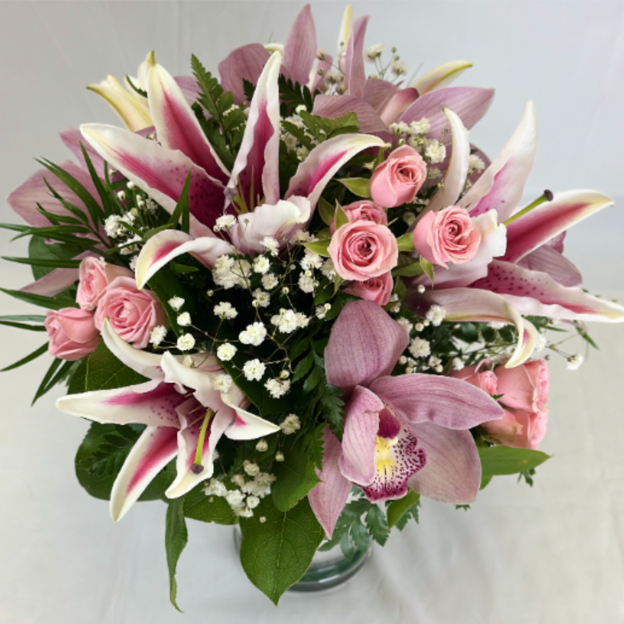 Pink lilies and roses in a clear glass vase