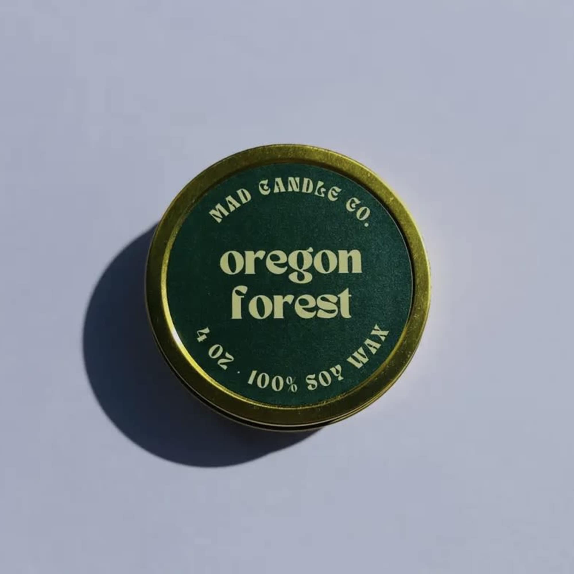 Round green candle tin labeled Oregon Forest