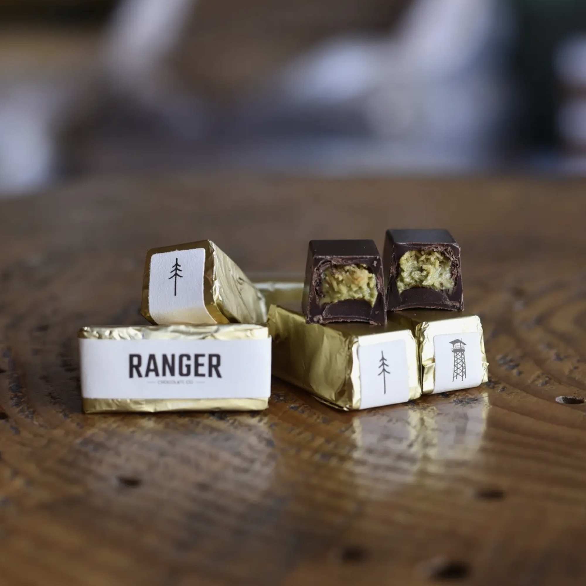 Assorted chocolate pieces in gold wrappers on a wooden table