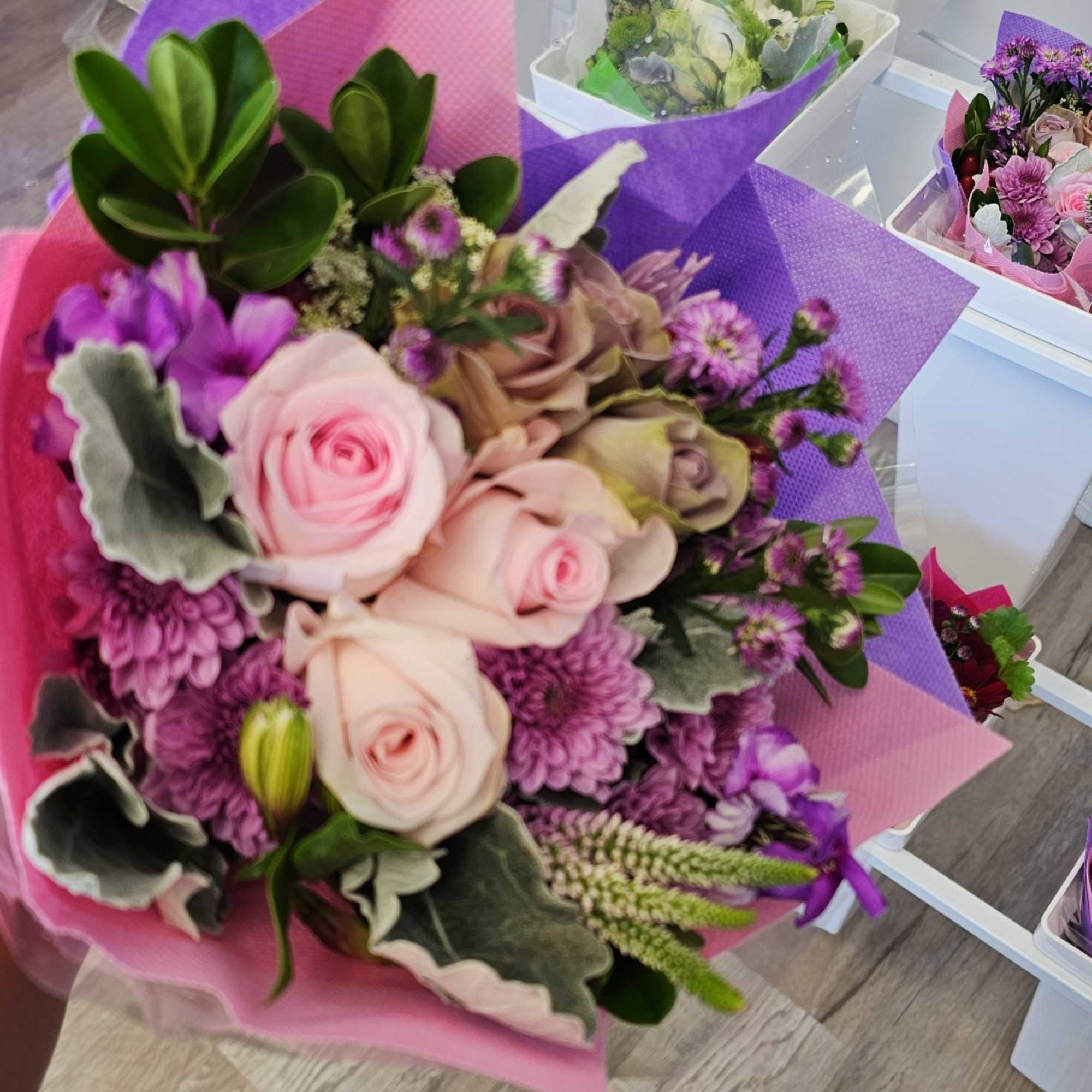 Bouquet of pink roses and purple flowers wrapped in pink and purple paper