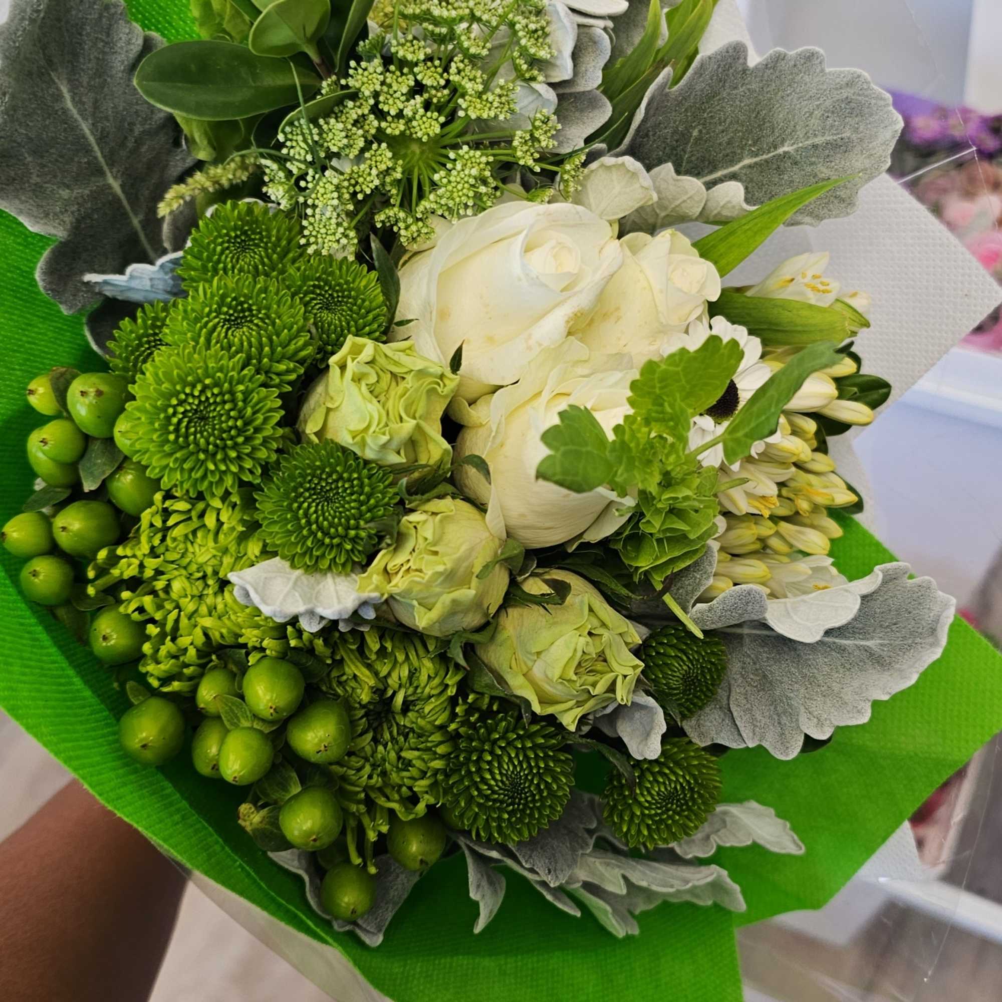 Green and white bouquet with roses and chrysanthemums wrapped in bright paper