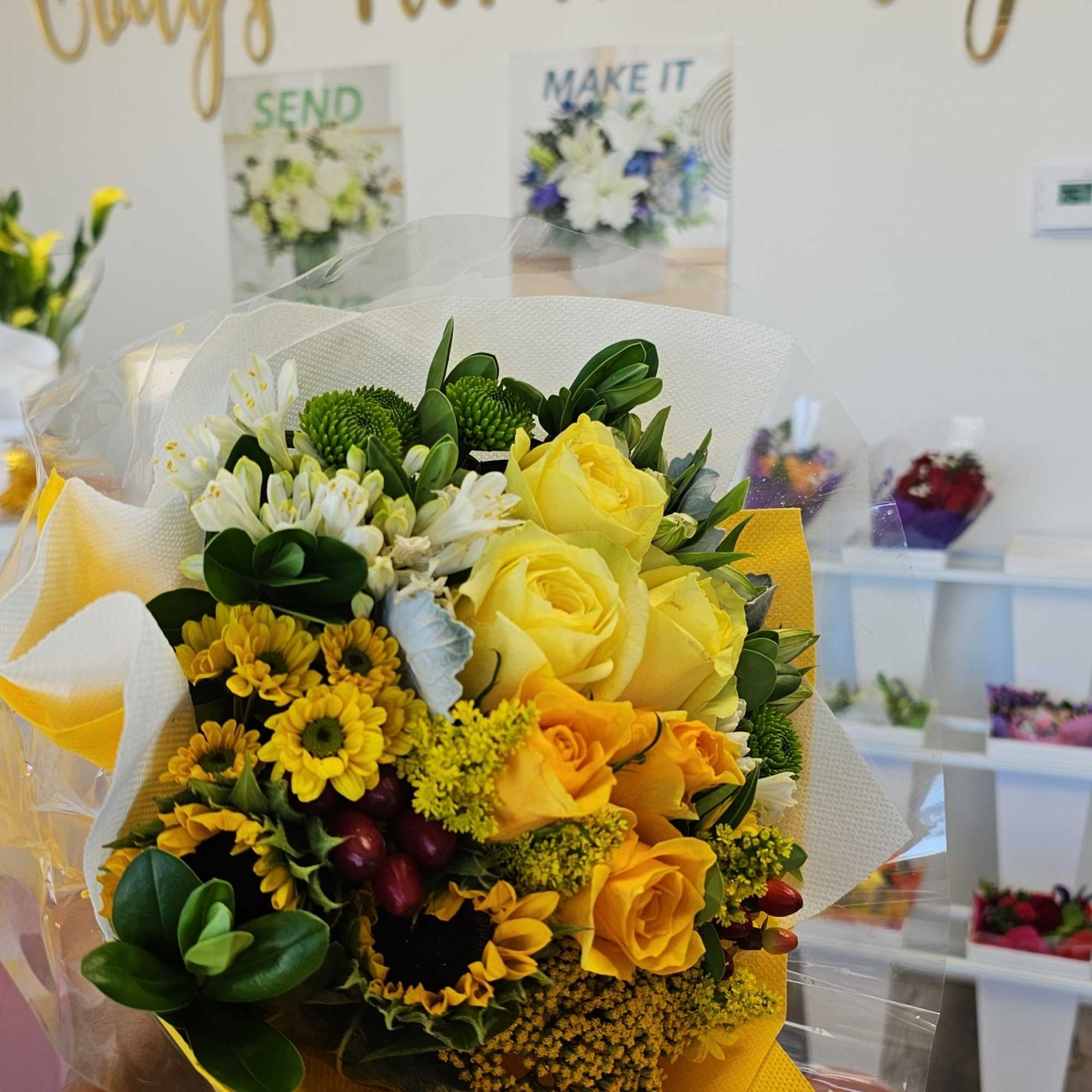 Yellow rose bouquet with white and green accent flowers wrapped in yellow paper