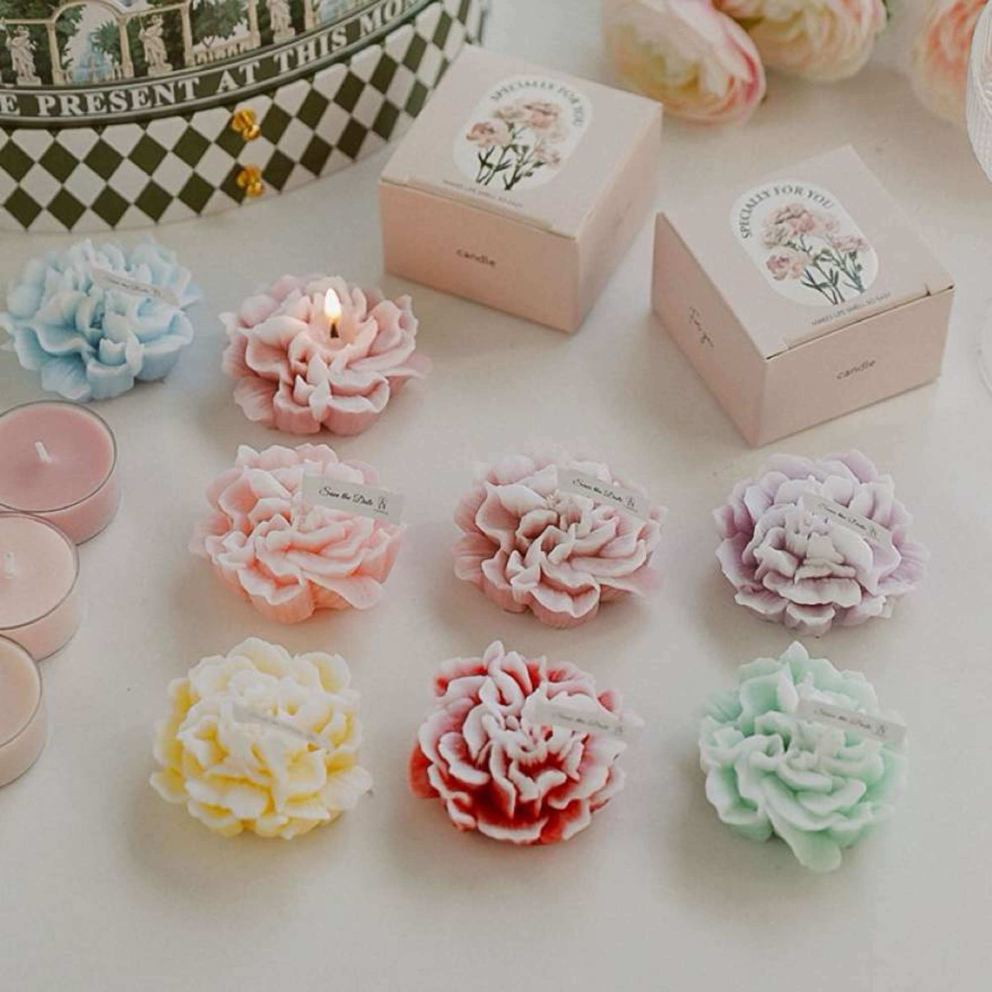Pastel flower-shaped candles and boxed candle gifts arranged on a table.