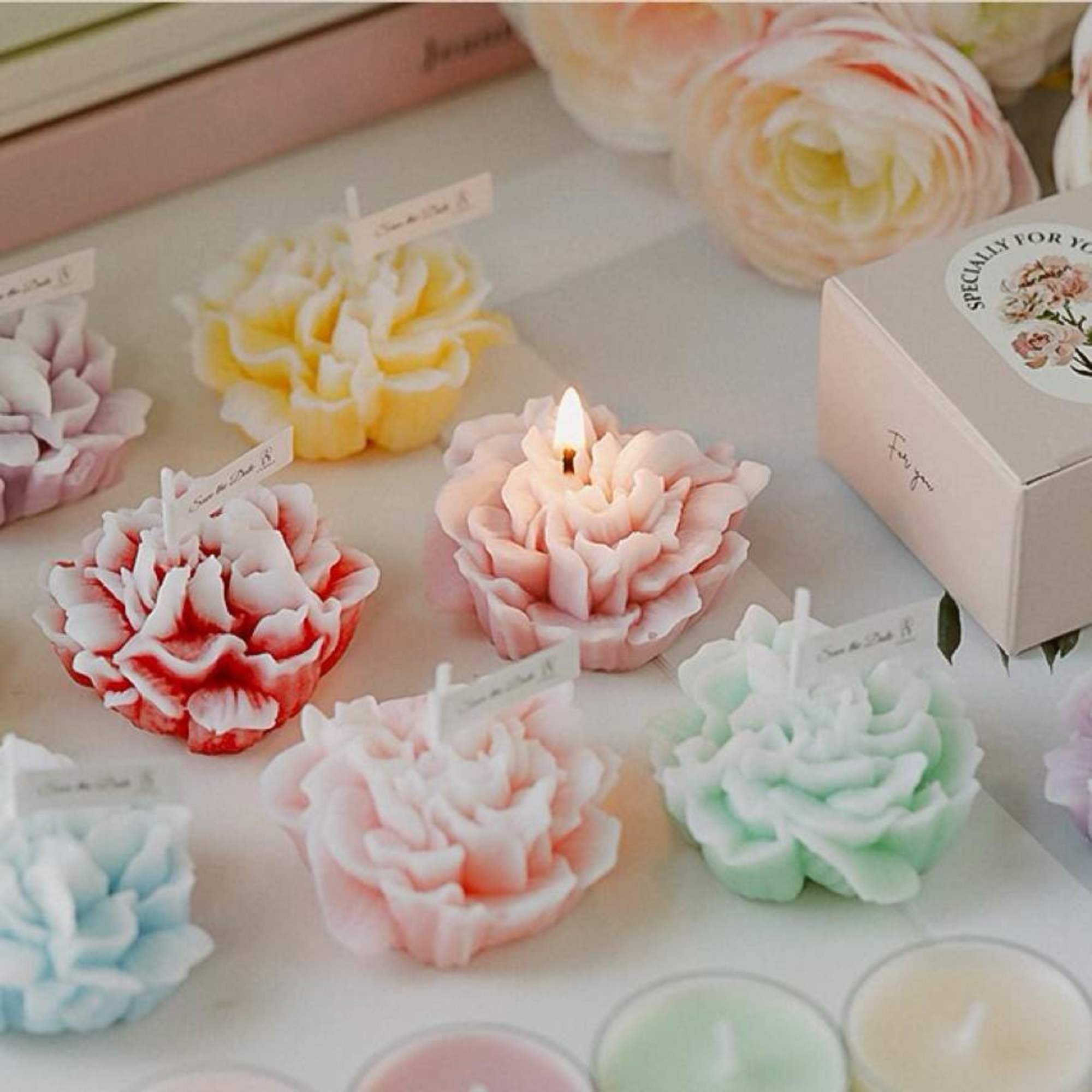 Assorted flower-shaped candles in pastel colors arranged in a box