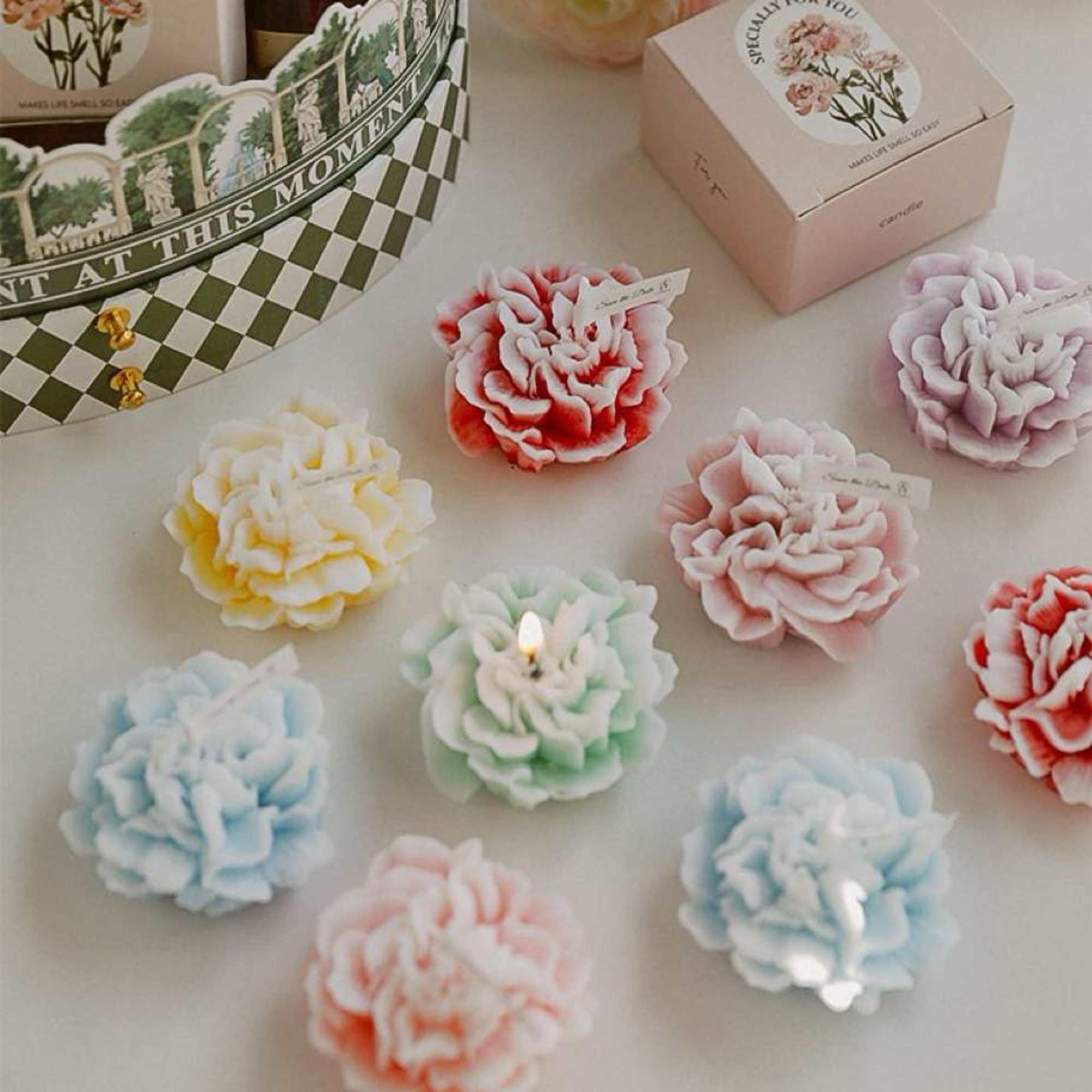 Pastel flower-shaped candles arranged on a tabletop with gift boxes