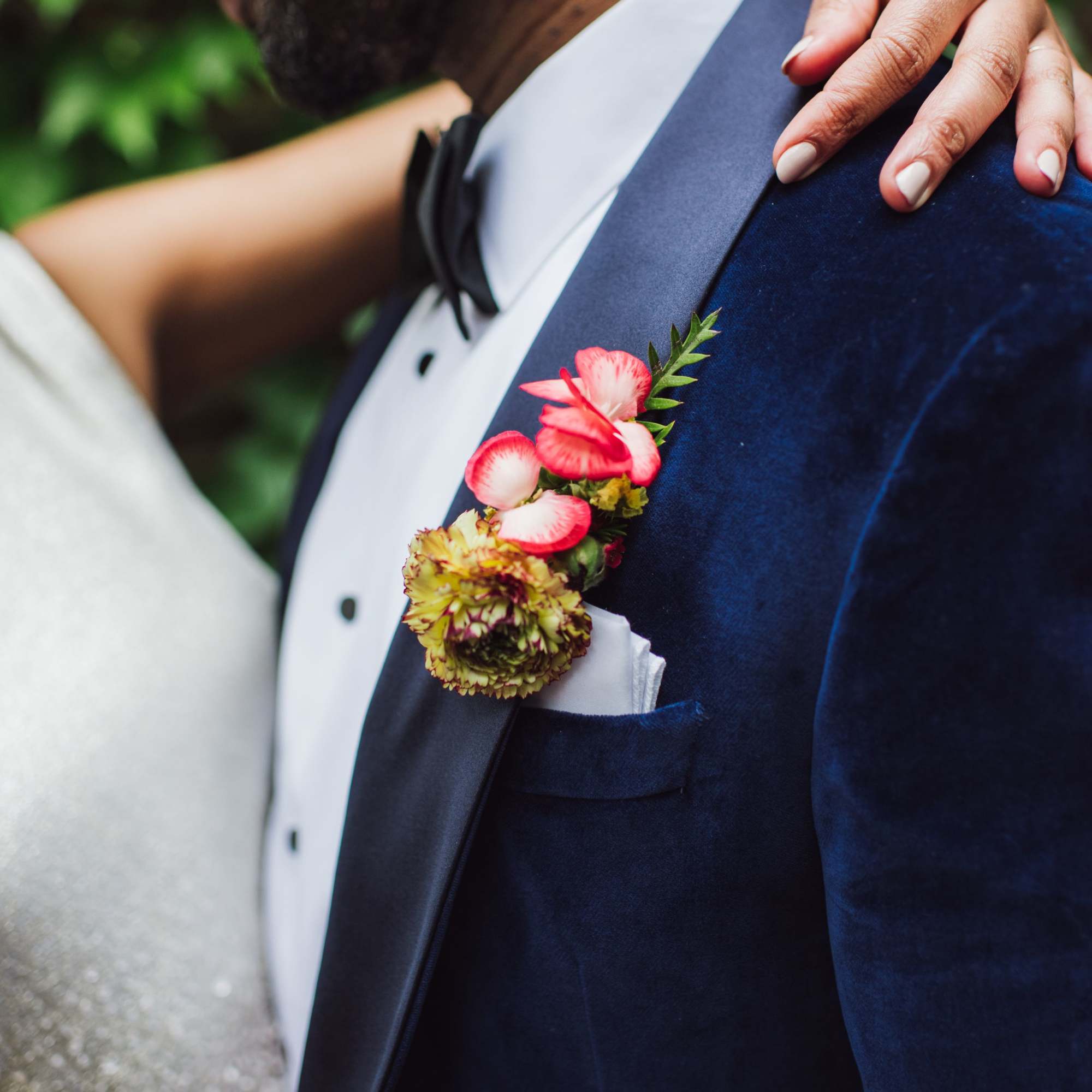 Boutonniere with pink and yellow flowers on a navy suit jacket